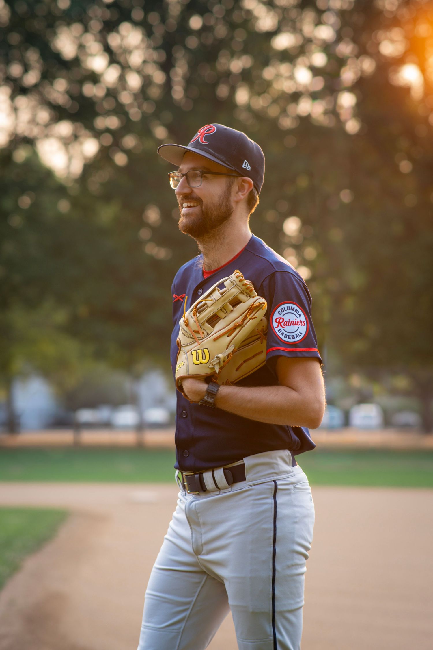 Baseball player standing on the field with a glove during a golden hour sports photography session in Portland, Oregon.
