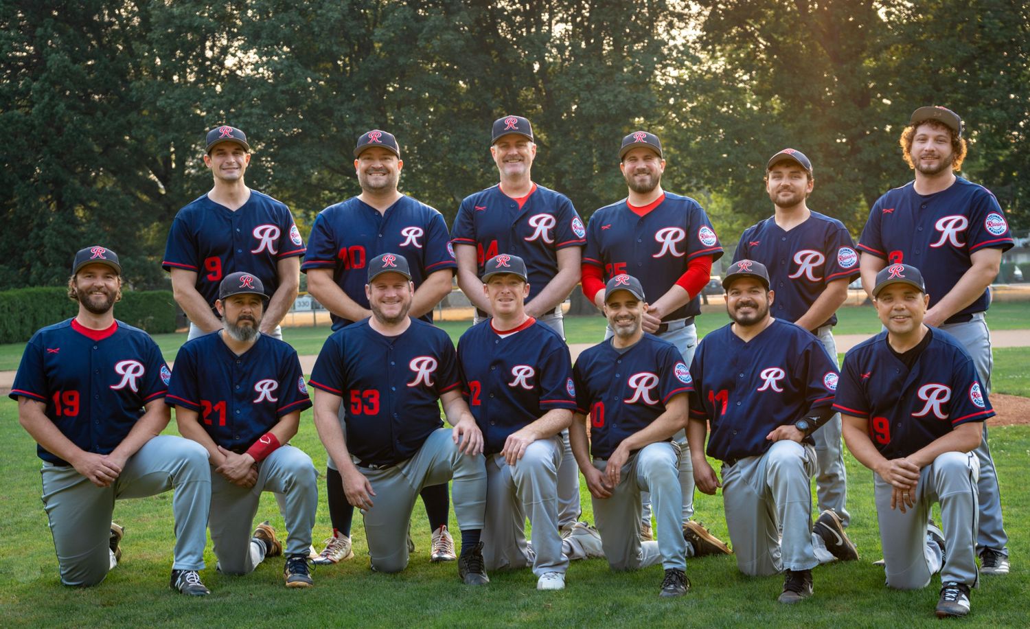 Adult baseball team posing together on the field for a team photo in Portland, Oregon.