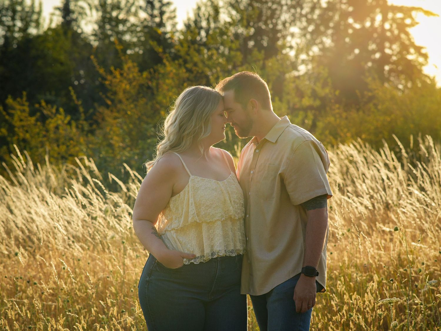 Couple touching foreheads in a sunlit field during a romantic golden hour photography session near Portland, Oregon