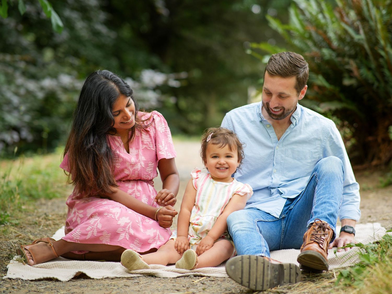 Family of three laughing together during a relaxed outdoor family photography session near Portland, Oregon