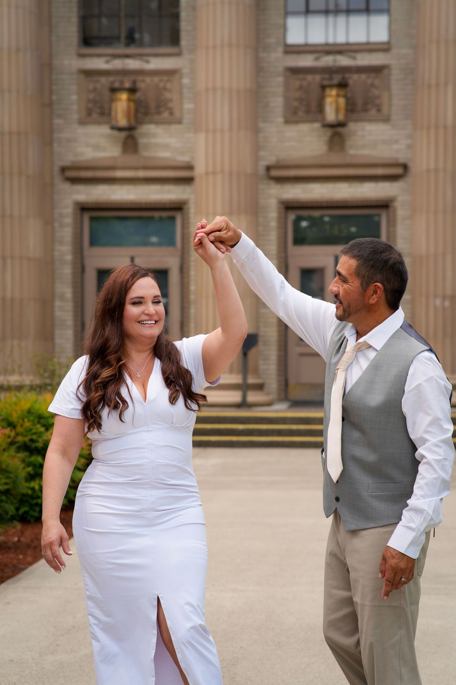 Groom twirling his bride outside the courthouse during their wedding portraits.