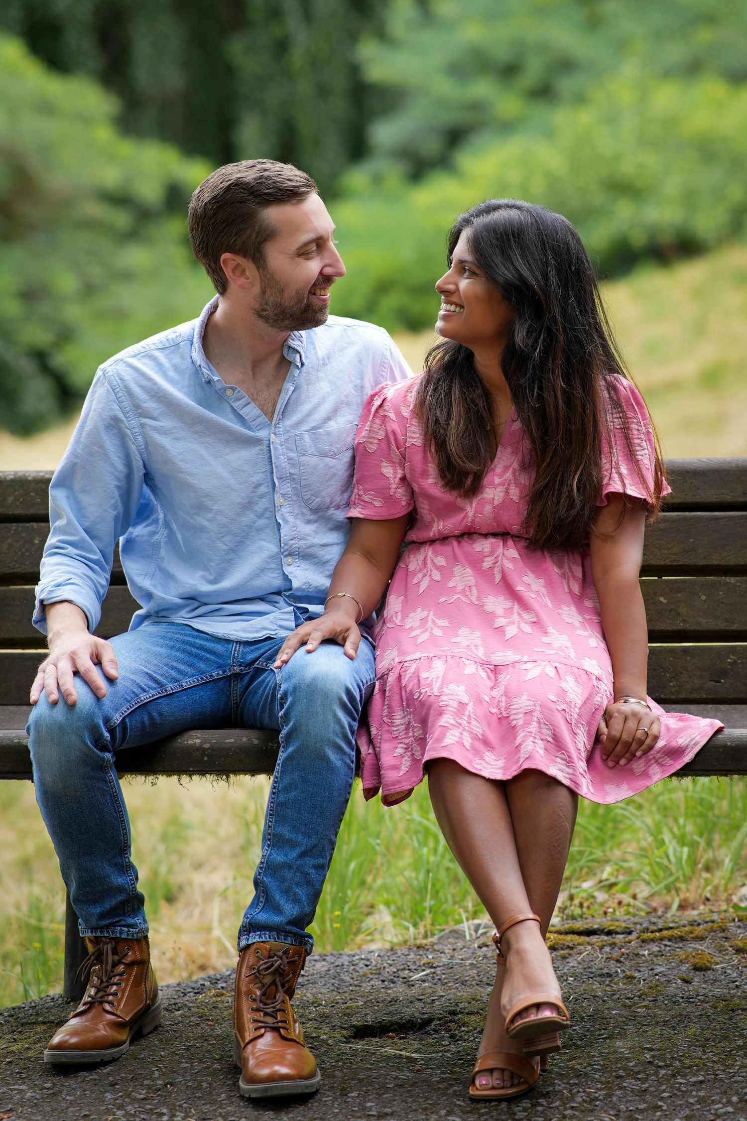 Couple sitting together on a park bench and smiling at each other during a relaxed outdoor photography session