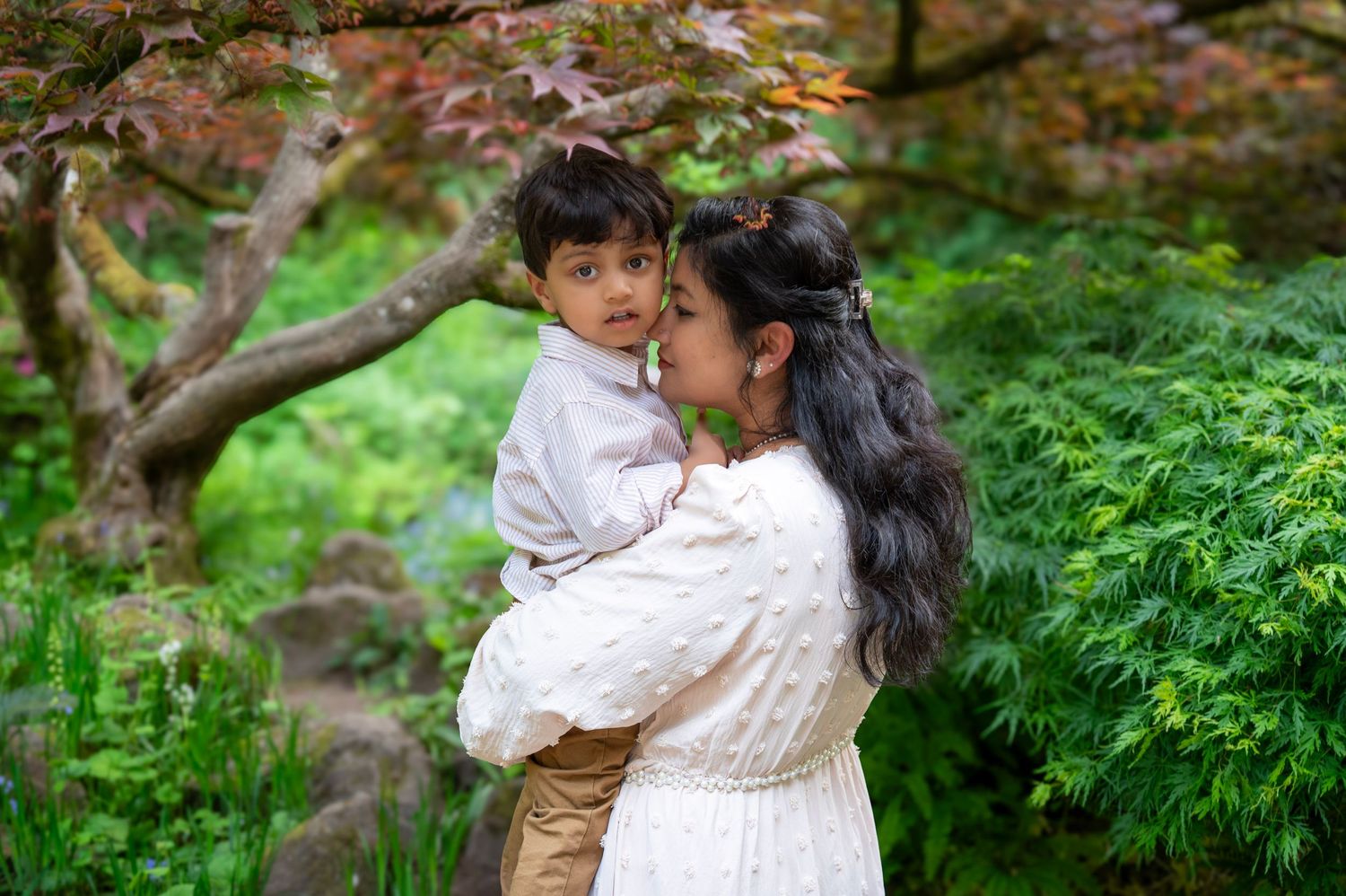 Mom cuddling her young son beneath a Japanese maple tree during an outdoor family photography session