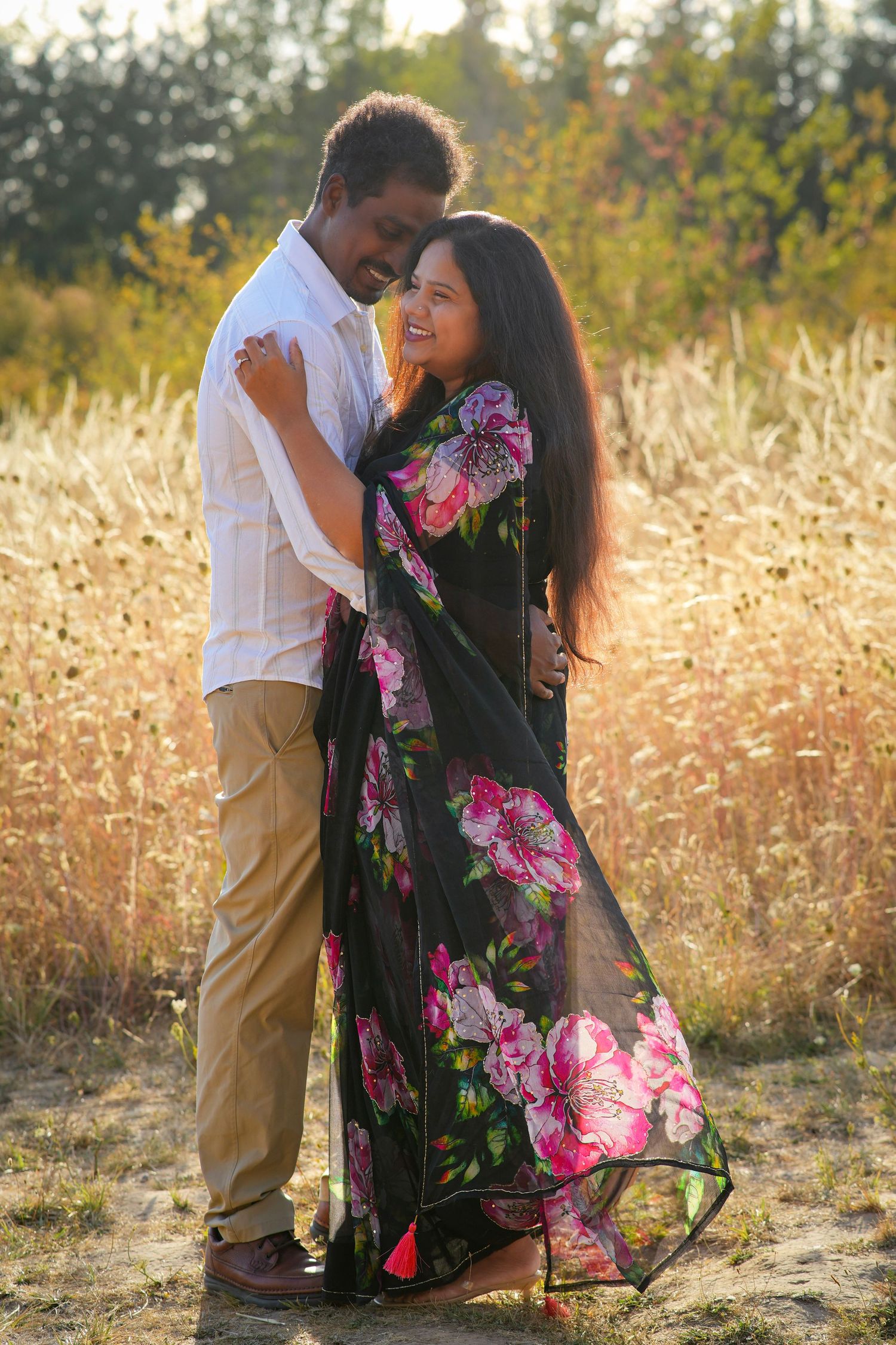 Couple sharing a quiet embrace surrounded by golden grasses during a sunset couples photography session