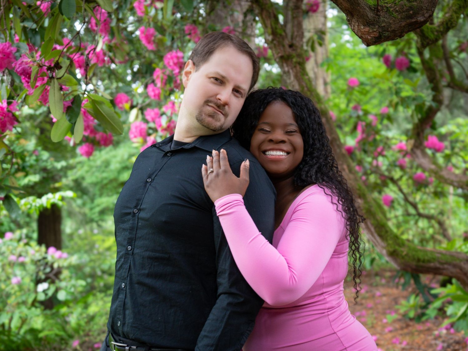 Couple embracing beneath blooming pink flowers during a spring couples photography session in Oregon