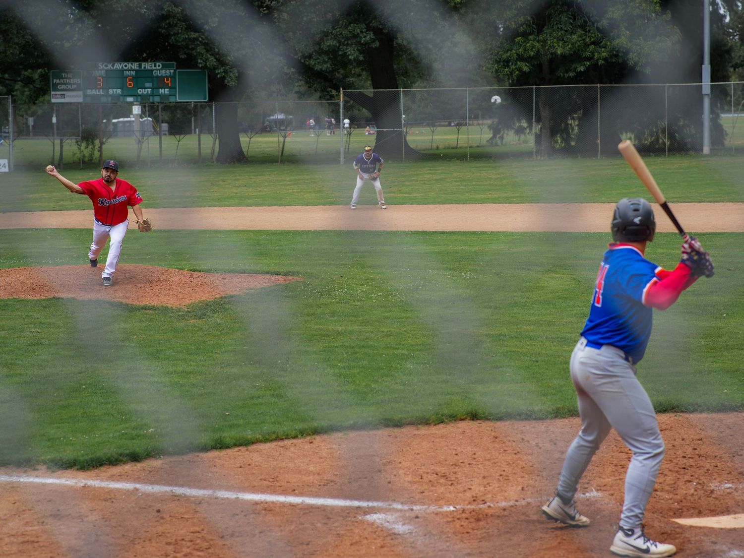 Baseball pitcher throwing toward a batter during a recreational baseball game in Portland, Oregon.