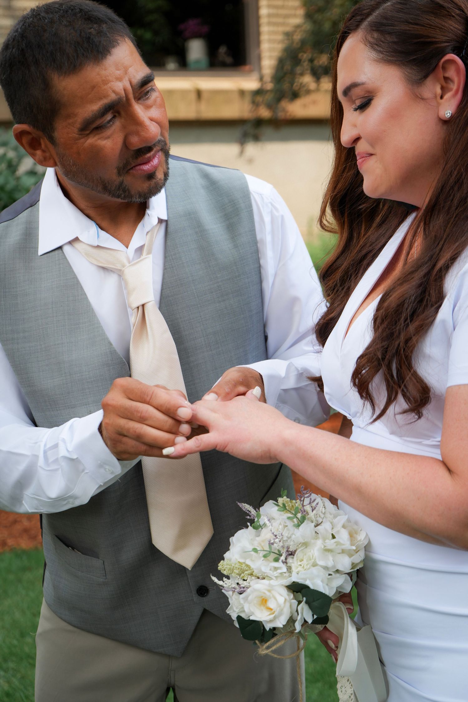 Groom holding his bride’s hand as the newlywed couple exchanges their wedding rings.