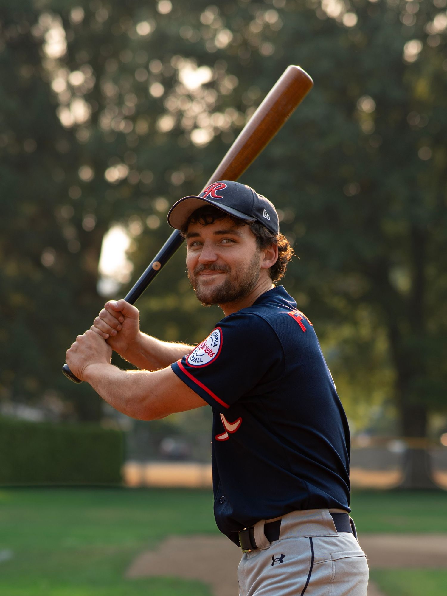 Baseball player smiling with a bat during an outdoor sports photography session in Oregon
