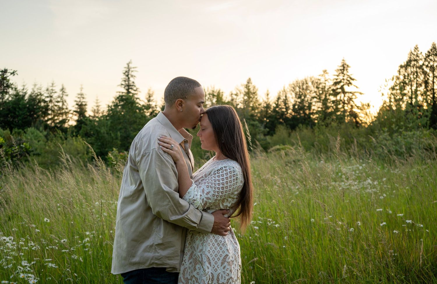 Couple embracing in a grassy field at sunset during an outdoor couples photography session near Portland, Oregon