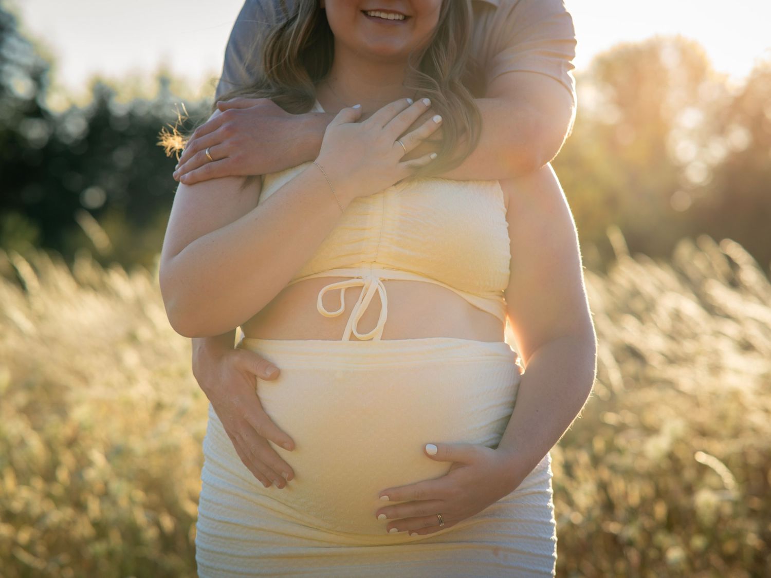 Close-up maternity portrait of a pregnant woman gently cradling her baby bump.