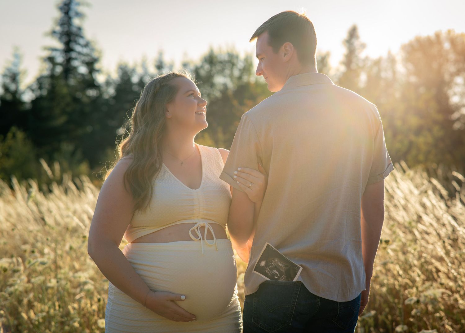 Expectant parents smiling together at sunset during an outdoor maternity photography session near Beaverton, Oregon