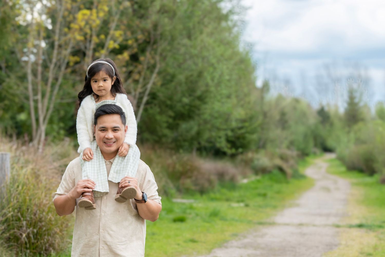 Dad carrying his young daughter on his shoulders as they walk along a scenic trail in Oregon