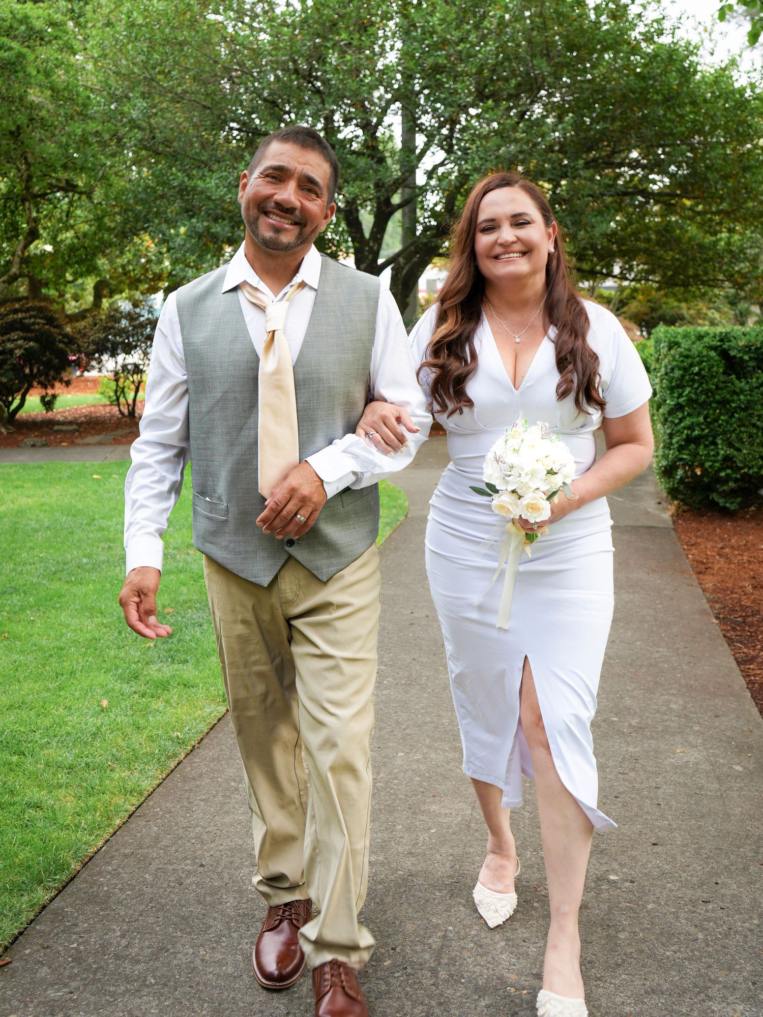 Newlywed couple laughing together while walking hand in hand after their wedding.
