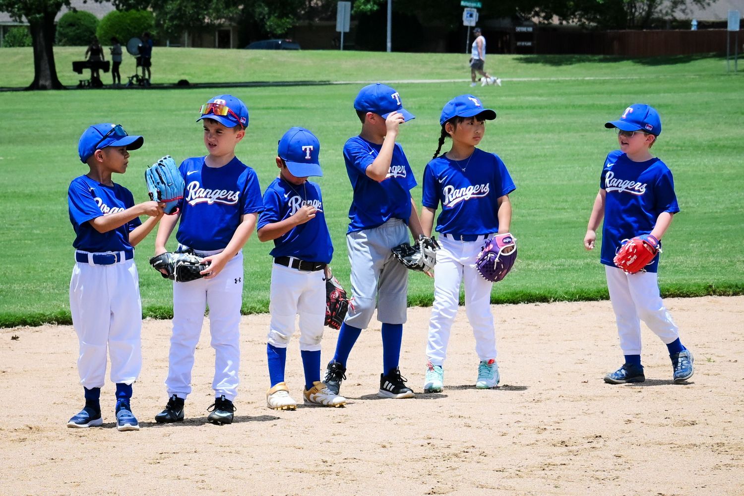Six young boys in blue Rangers baseball uniforms standing on a baseball field during a little league game.