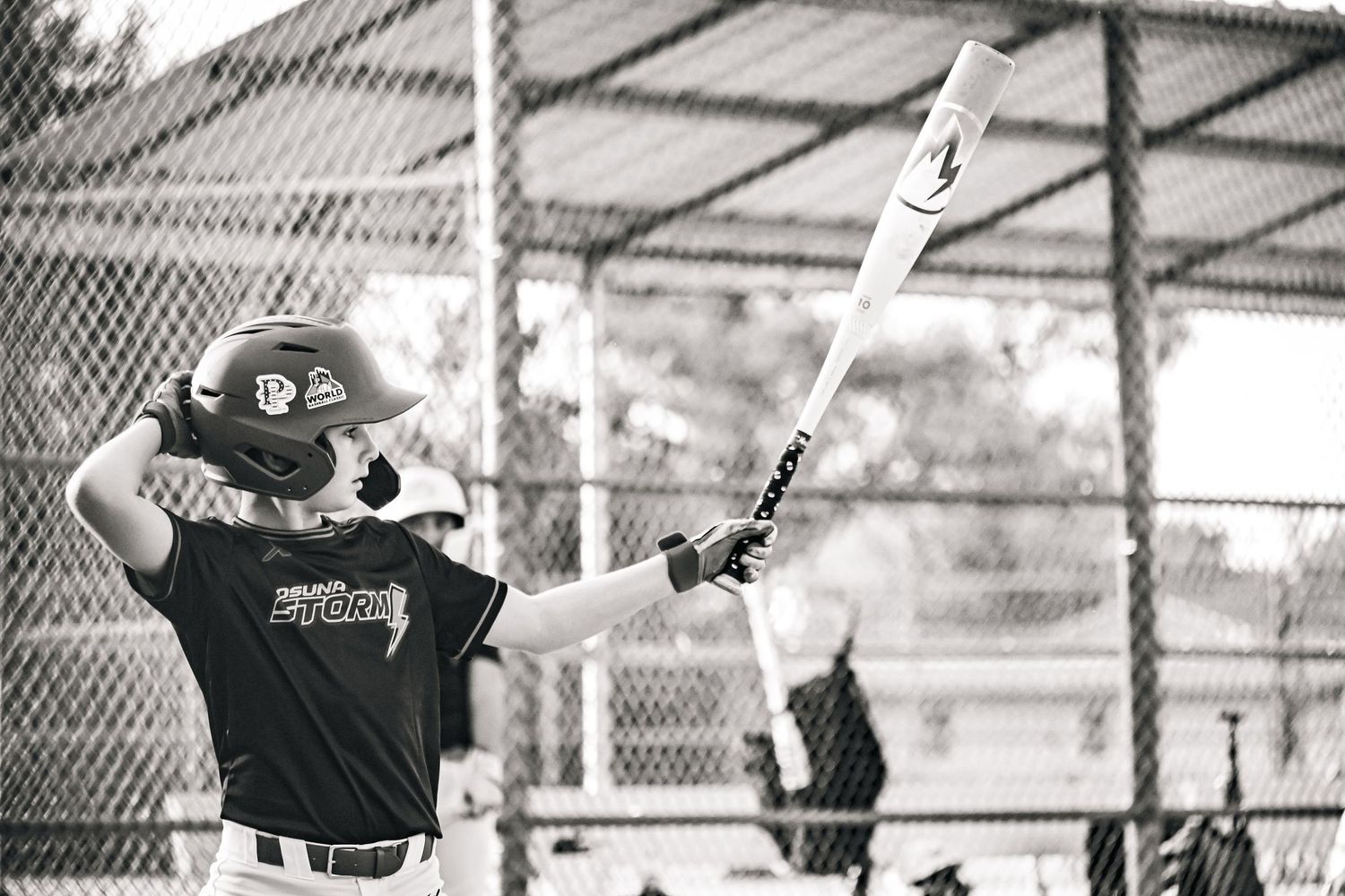 Black and white photo of a youth baseball player swinging a bat during a game.