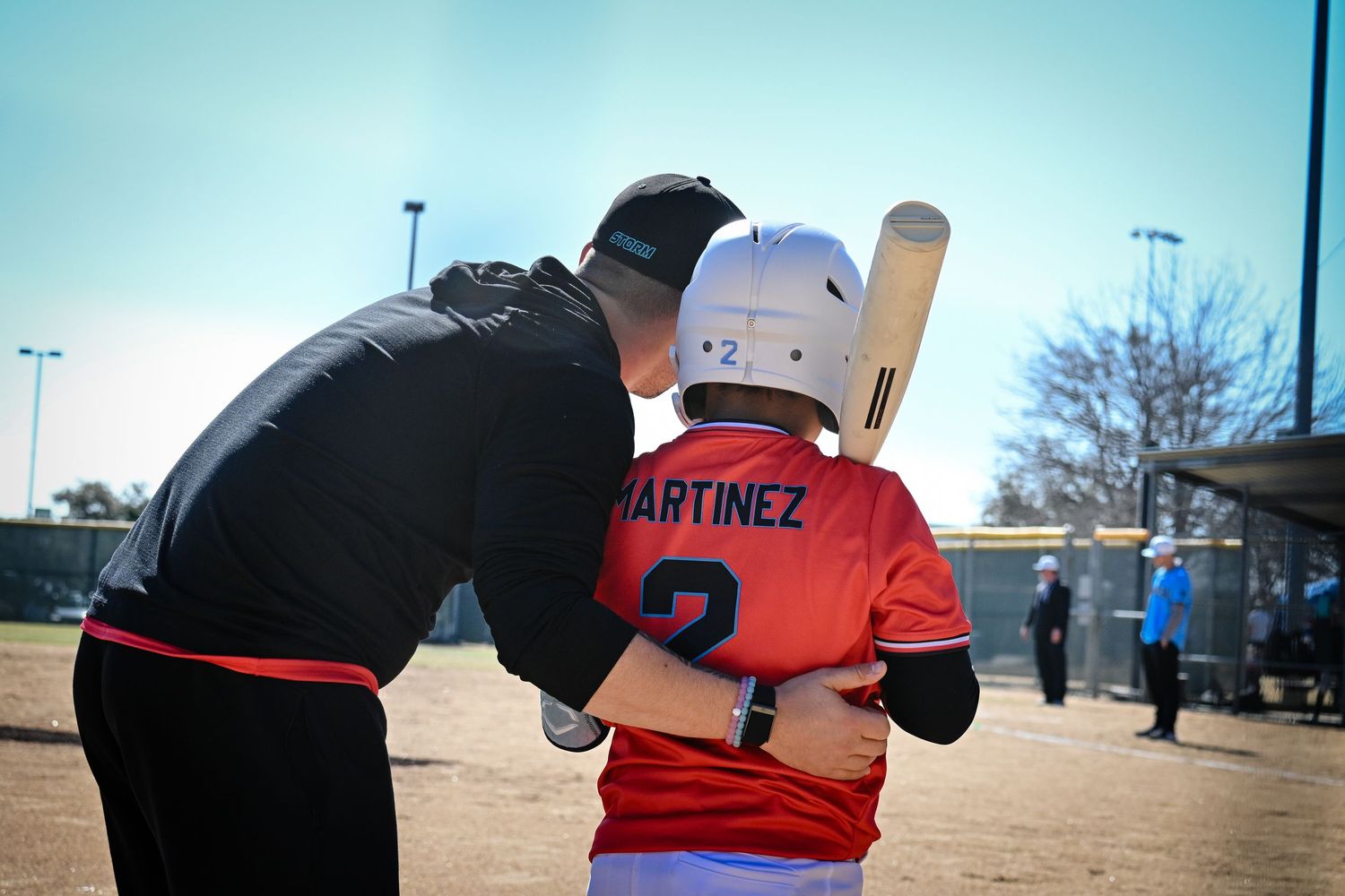 Baseball coach instructs young player Martinez number 2 on batting technique during a youth baseball game.