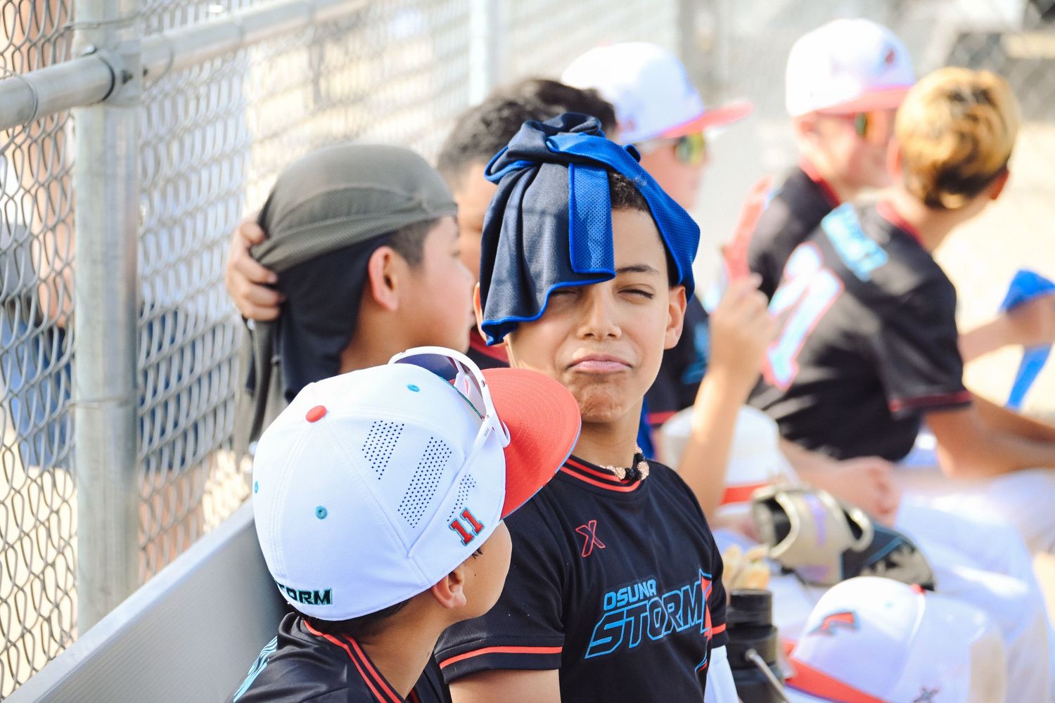 Youth baseball player has an ice pack applied to his head in the dugout after an injury during a game.