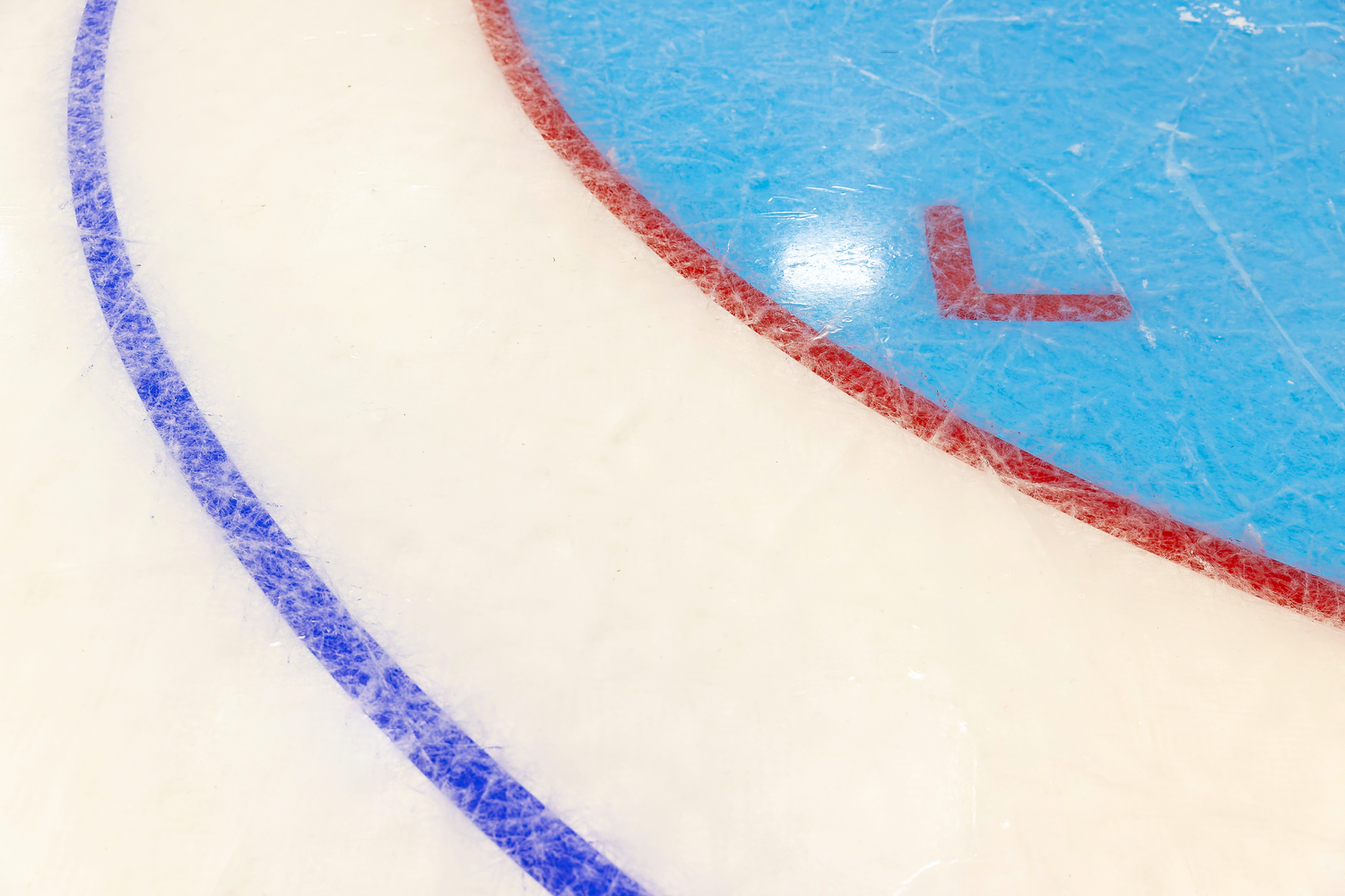 Close-up of an ice hockey rink surface showing blue and red circle lines.