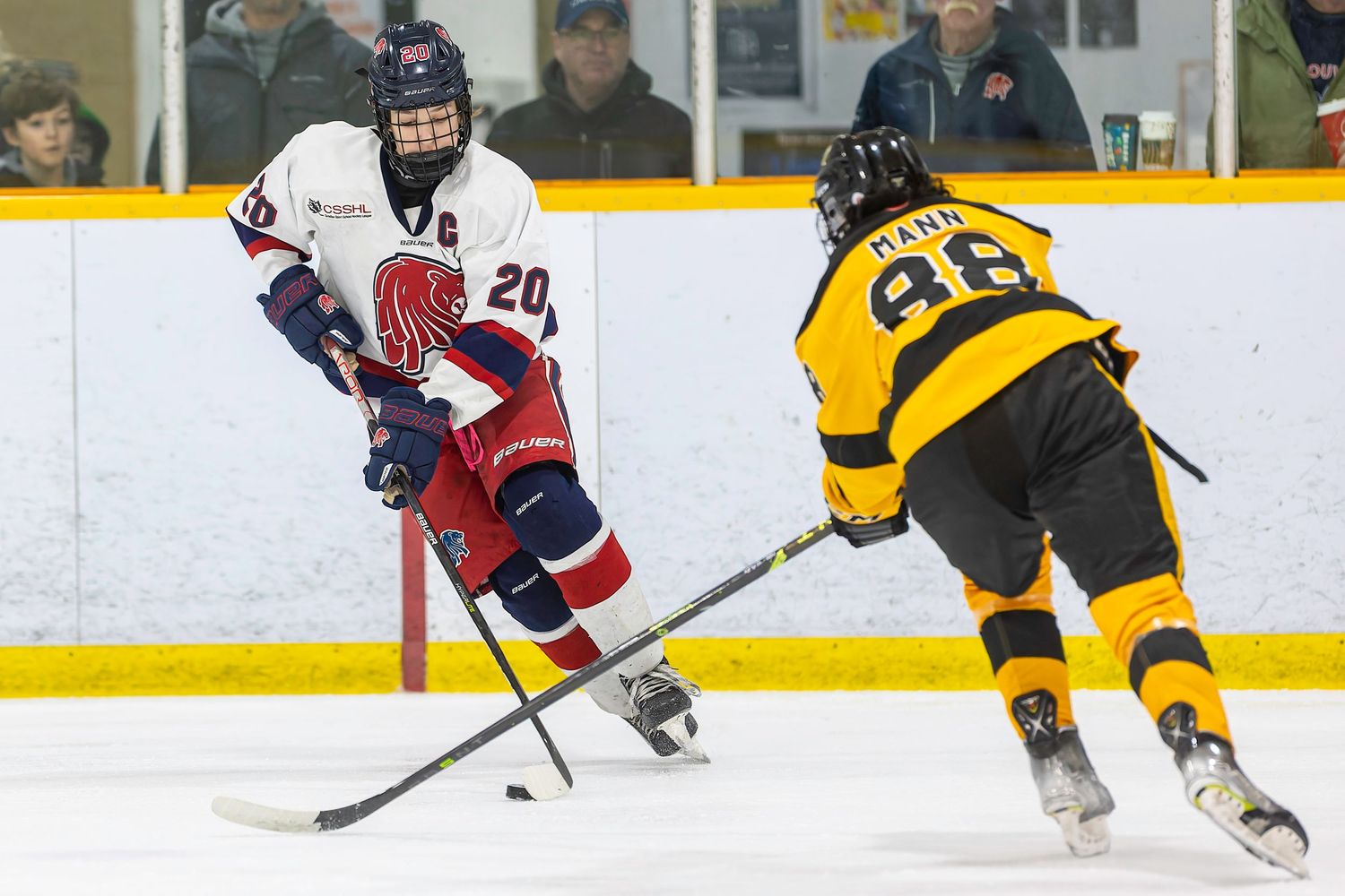 Two ice hockey players compete for the puck, one in white jersey #20, the other in yellow #48, on an indoor rink.