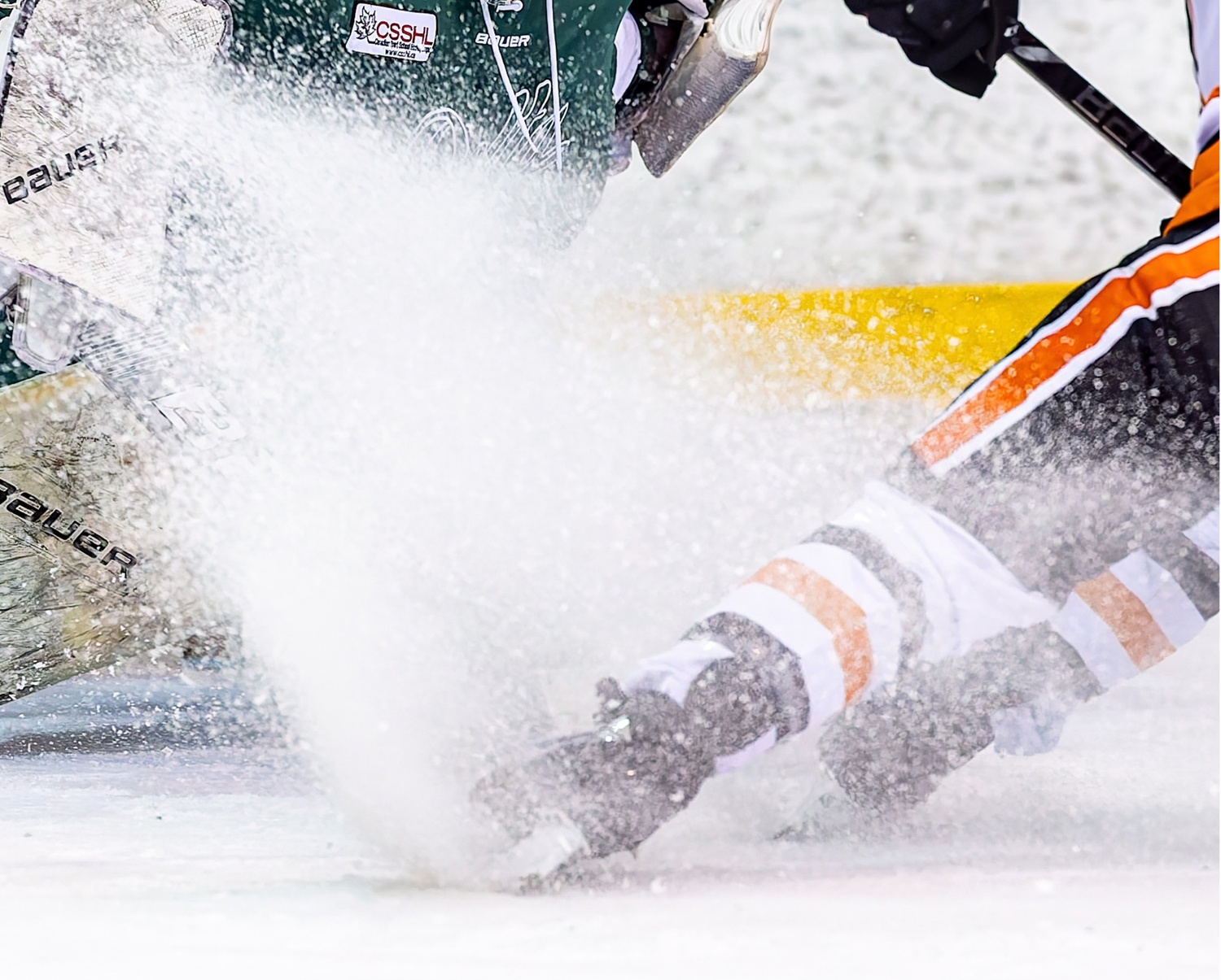 Ice hockey players collide on the rink, sending a dramatic spray of ice shavings into the air during an intense game.