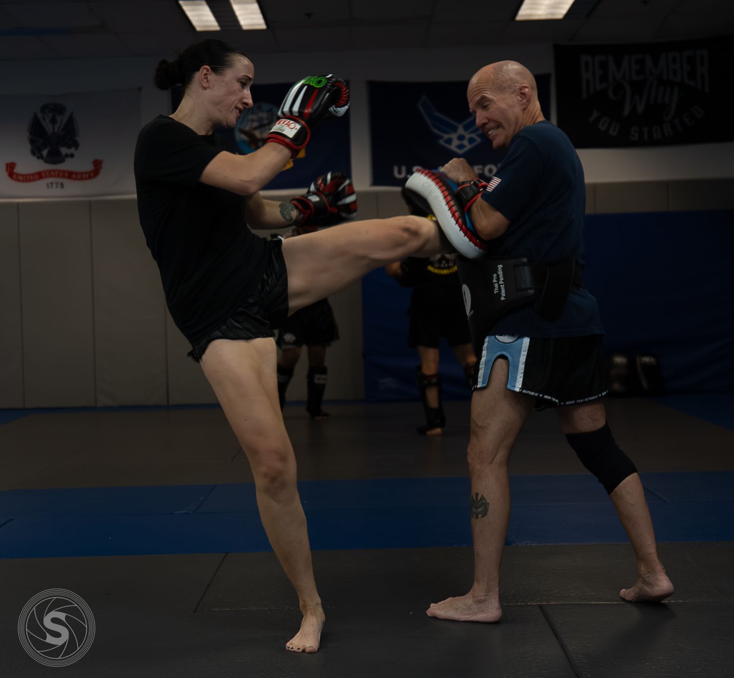 Two MMA fighters practice Muay Thai kickboxing techniques in a martial arts gym during a training session.