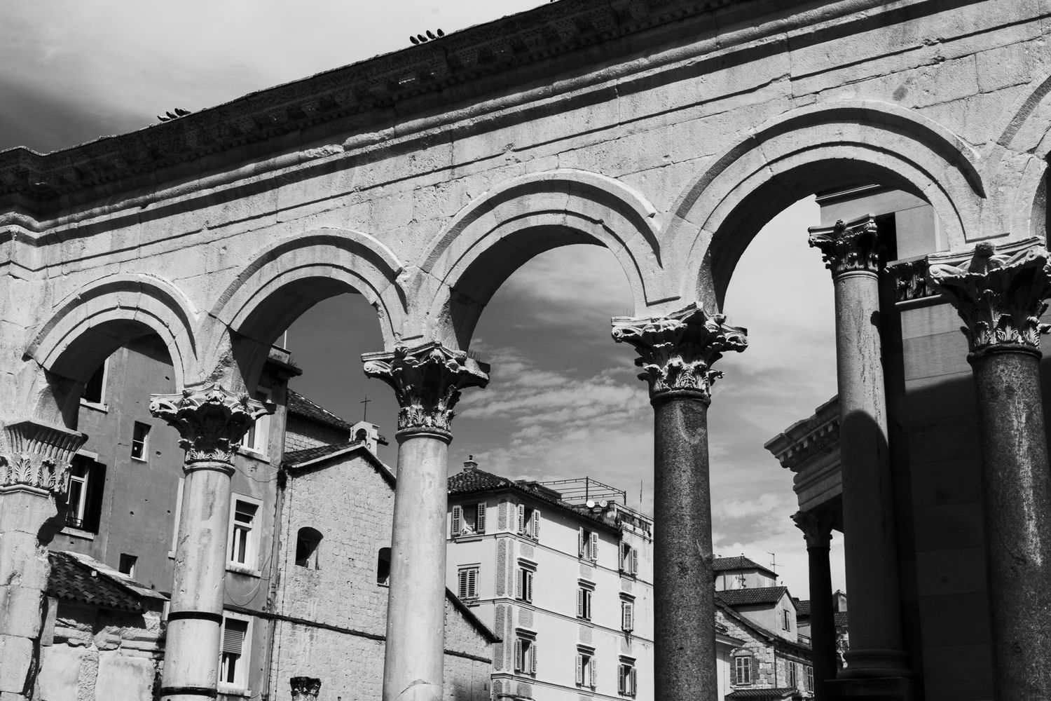 Black and white photo of ancient Roman arches and Corinthian columns at Diocletian's Palace in Split, Croatia.