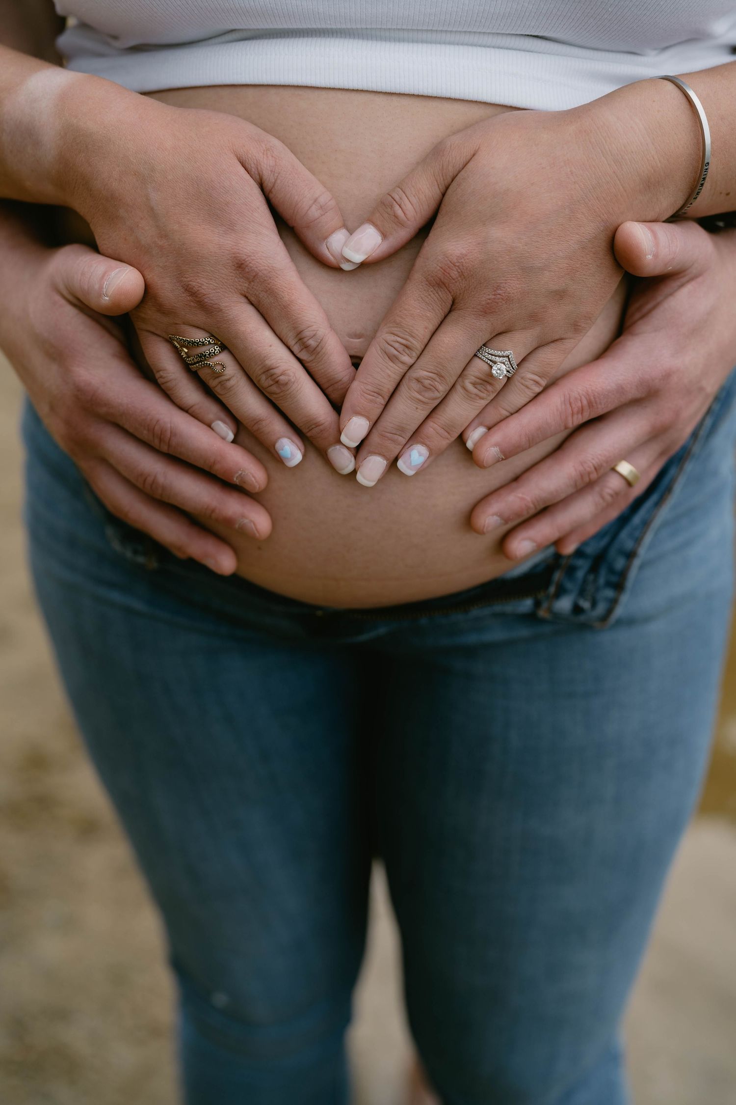 Close-up shots of hands gently cradling a pregnant belly in blue jeans.