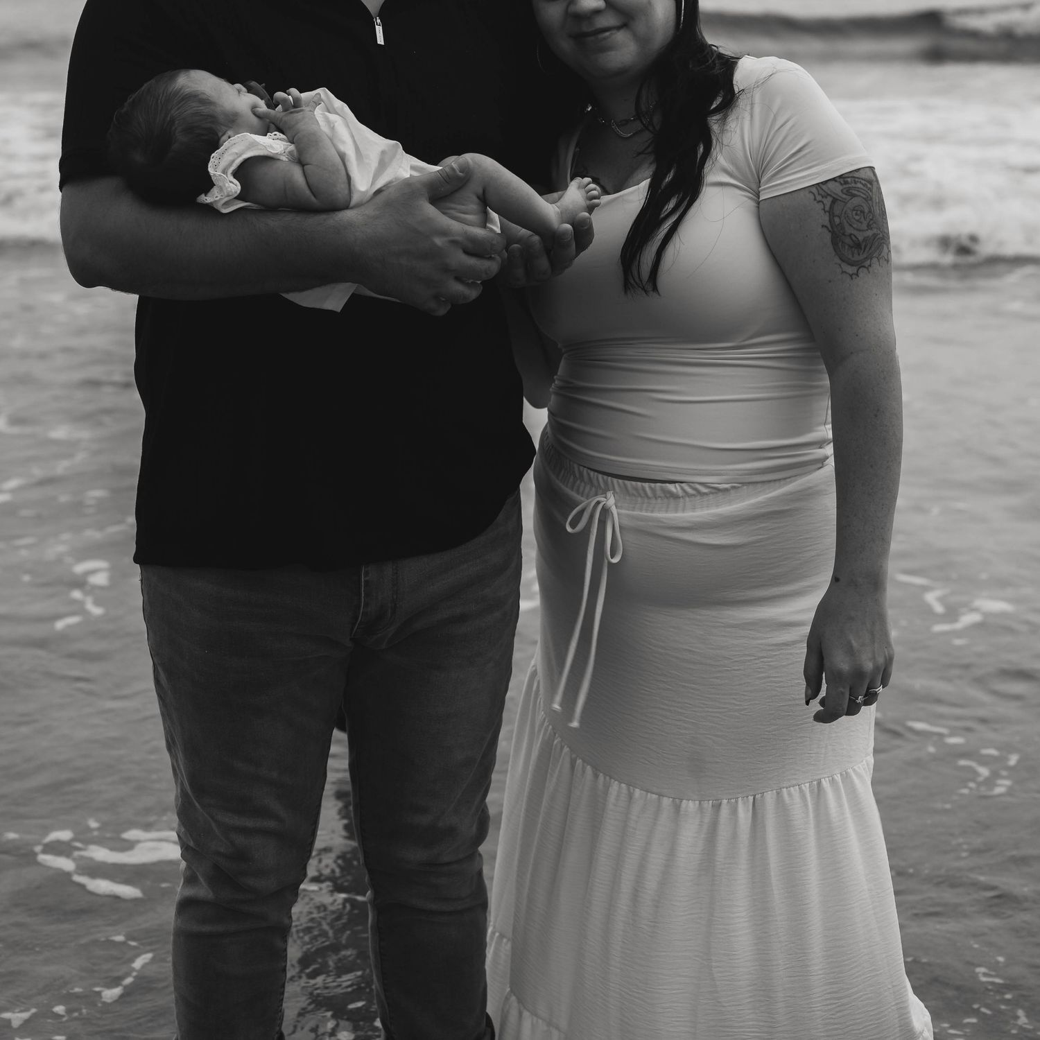 Black and white portrait of family members standing together by the ocean.