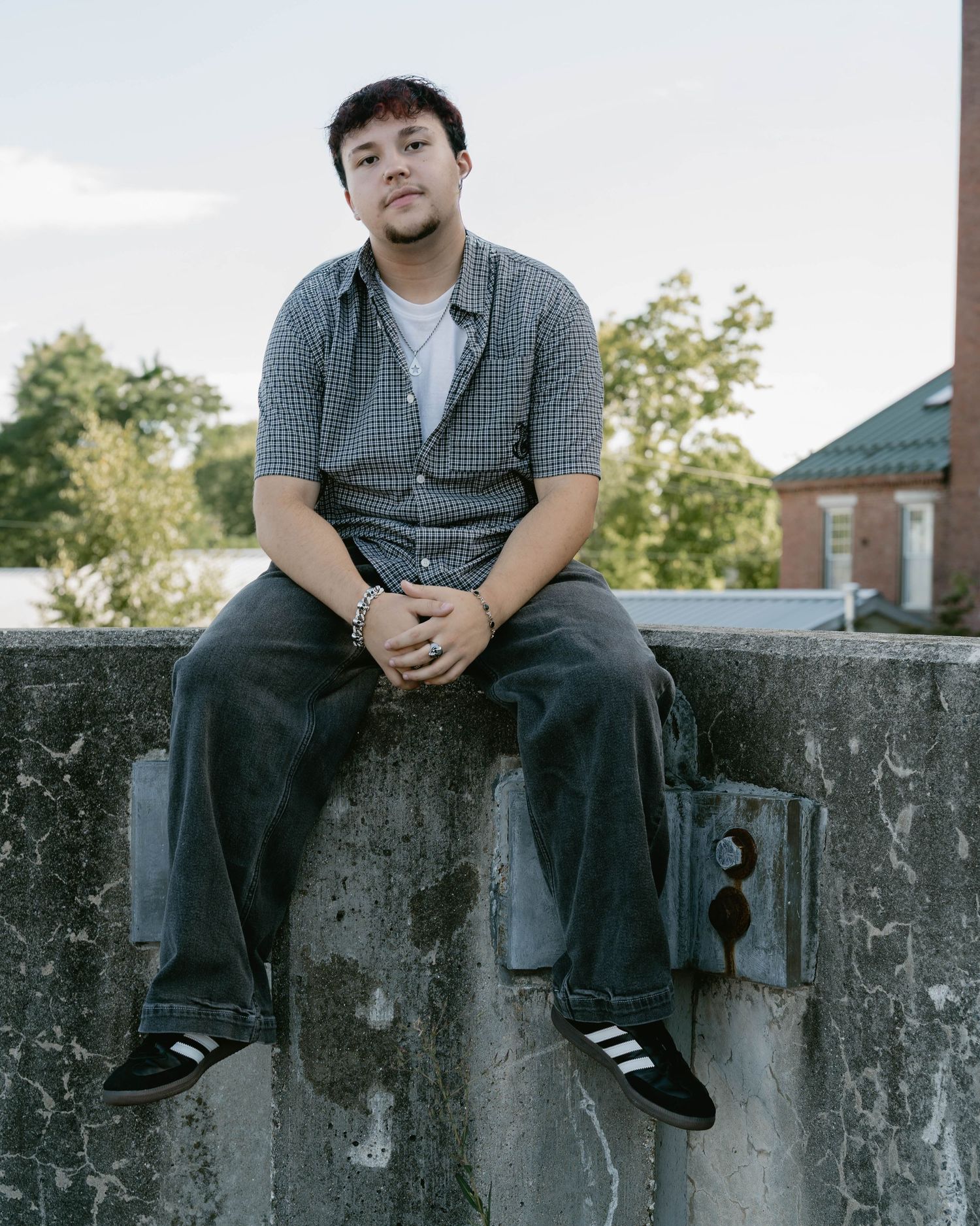 teen sitting on ledge in urban parking lot setting, capturing relaxed, candid moments.