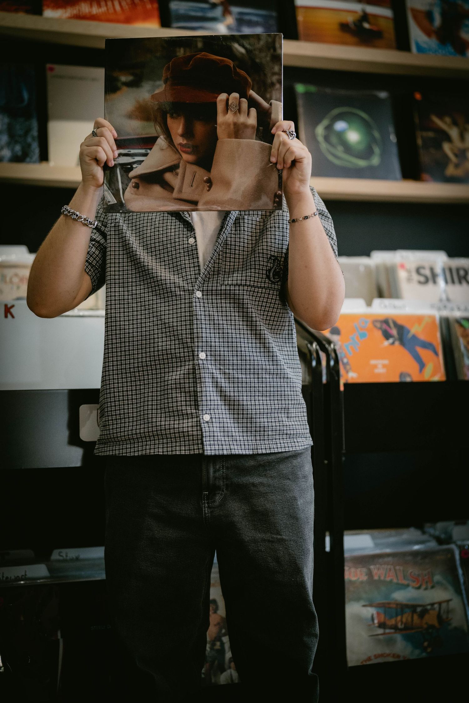 Teen holding a record in a vintage shop, enjoying a fun, urban senior session.