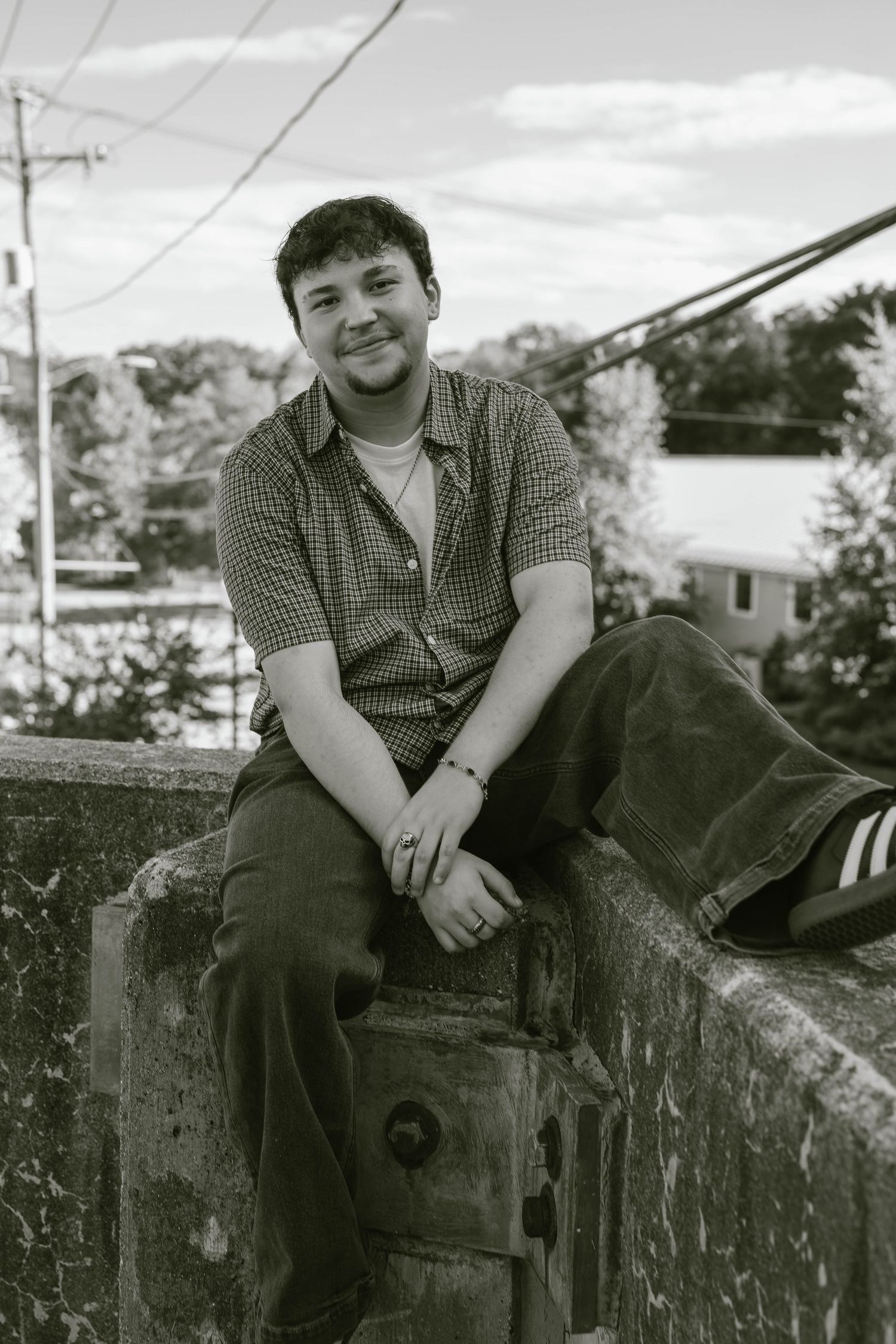 Senior sitting on a ledge in a parking lot, smiling and relaxed during an urban portrait session.