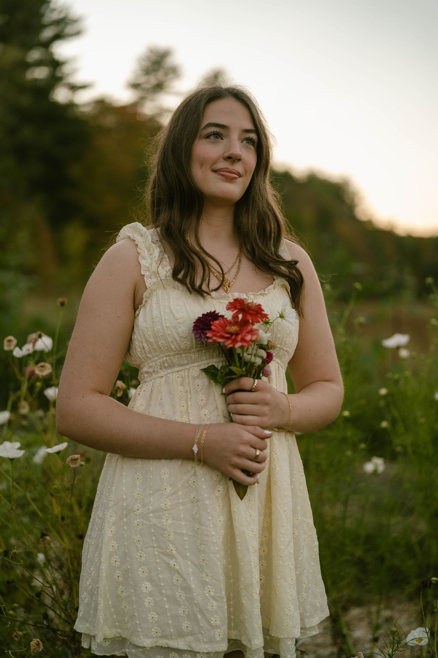 Senior holding a few wildflowers, standing in a sunlit flower field.
