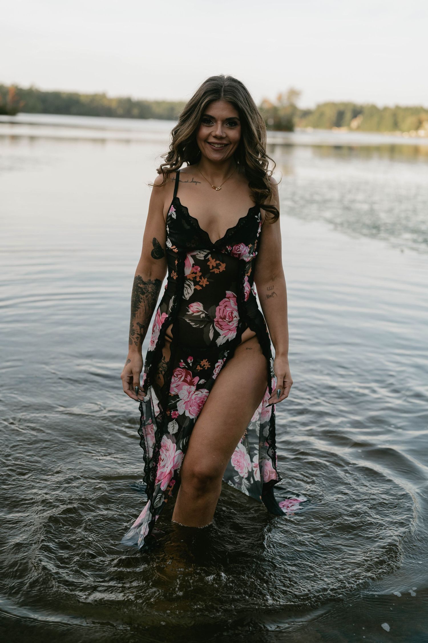 A summer photoshoot in a black floral dress while standing in shallow water.