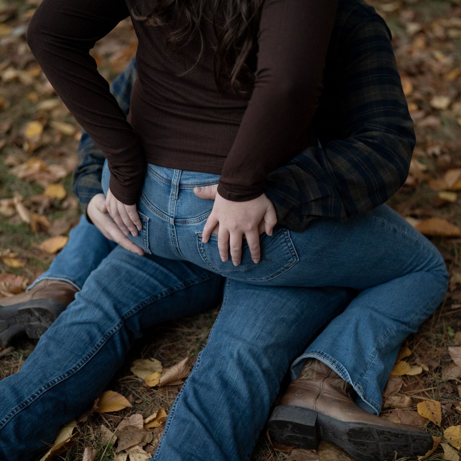 Close-up of denim jeans and boots on autumn leaves.