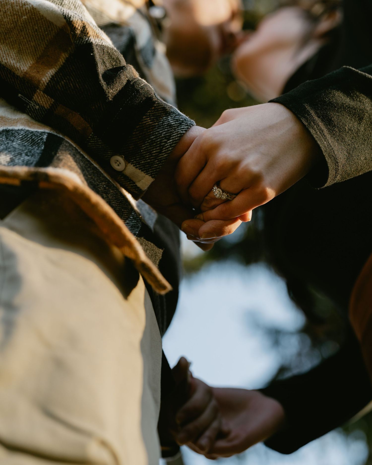 Close-up shot of hands exchanging rings during an intimate outdoor moment.