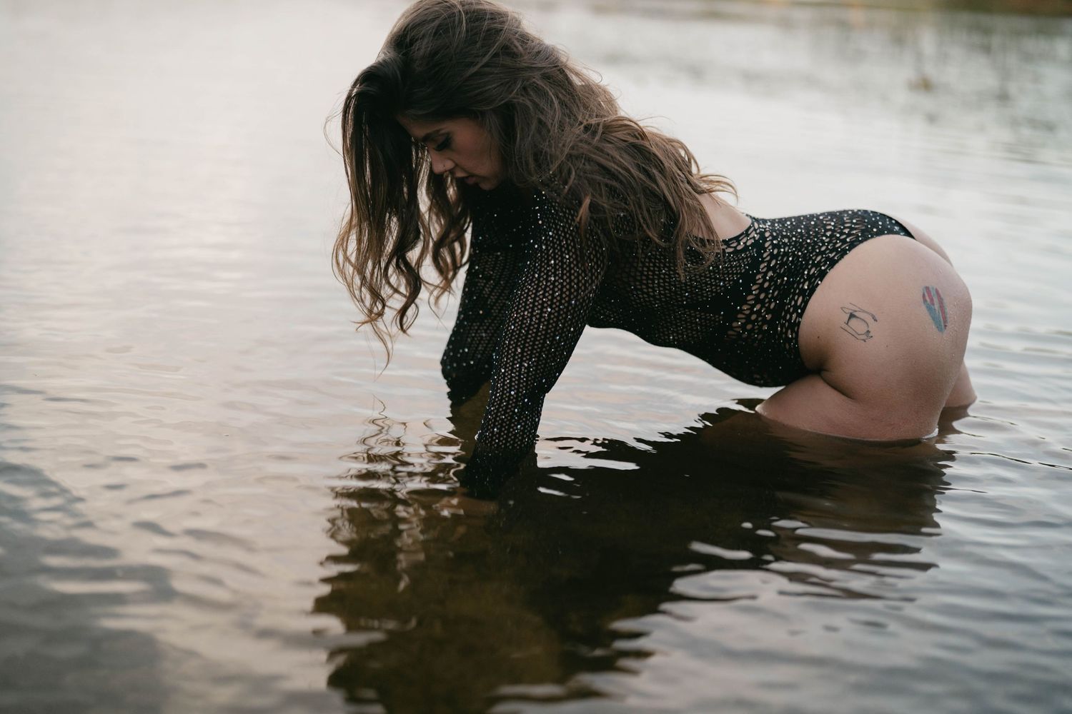 Artistic water photoshoot featuring a black mesh swimsuit at sunset.