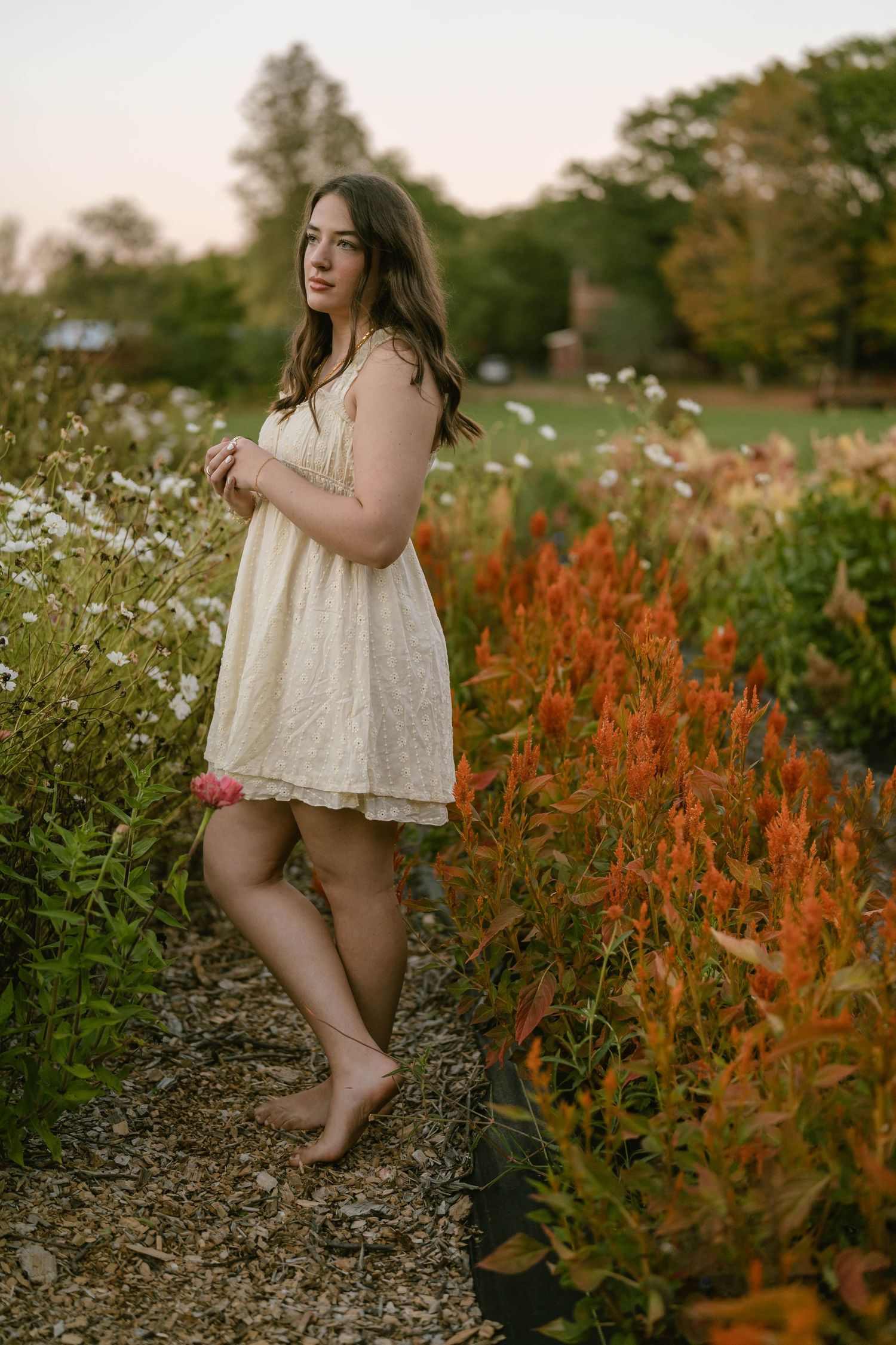 Teen twirling with flowers in hand, captured in vibrant outdoor portrait.