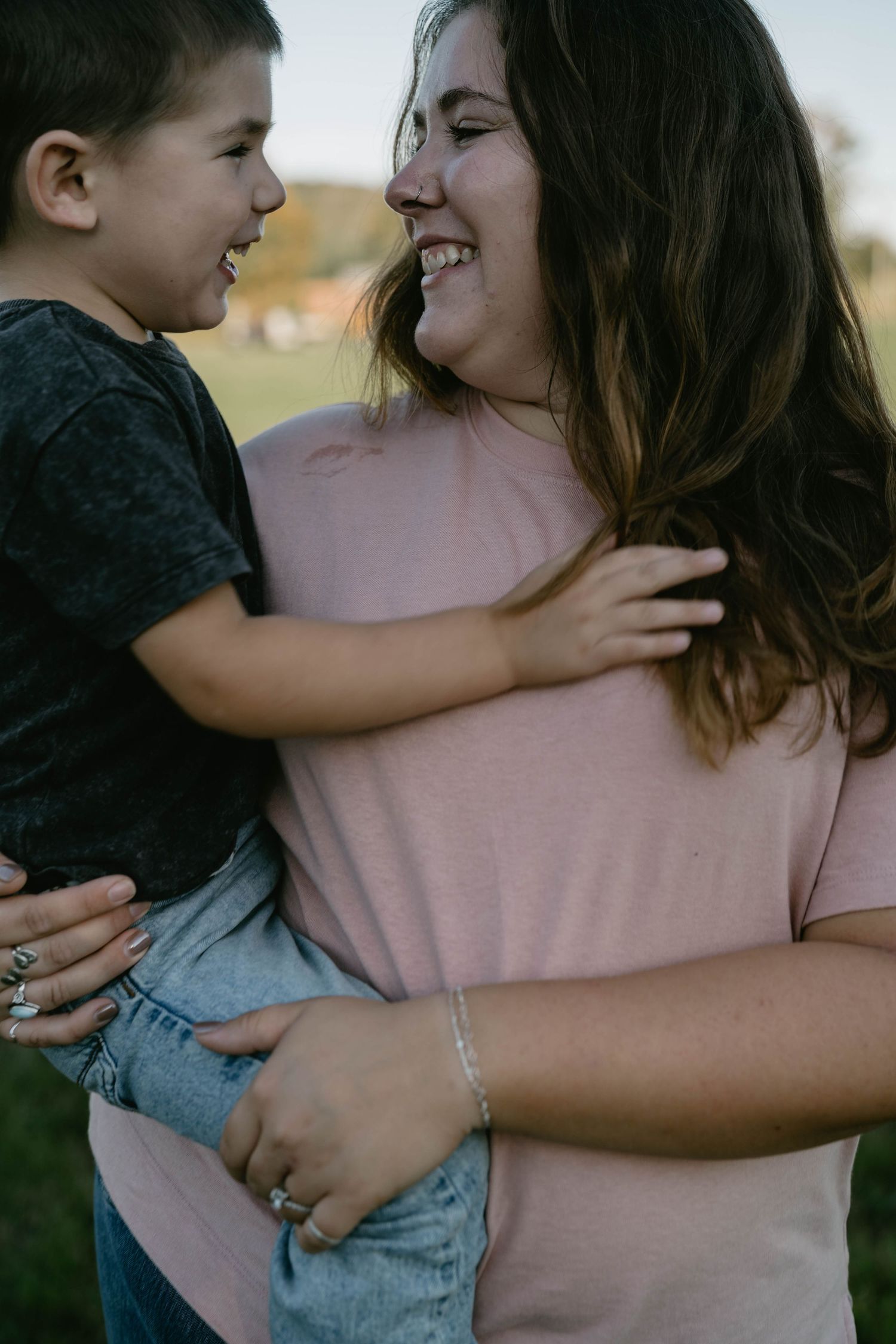 A tender moment between parent and child wearing pink and grey outfits while embracing outdoors.