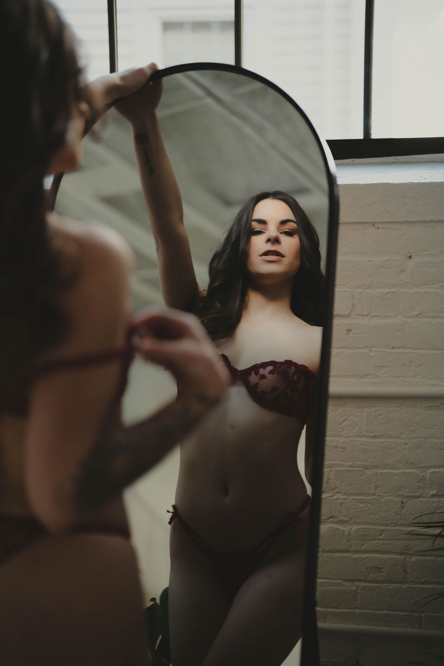 Artistic boudoir photo session with dramatic lighting and mirror reflections.