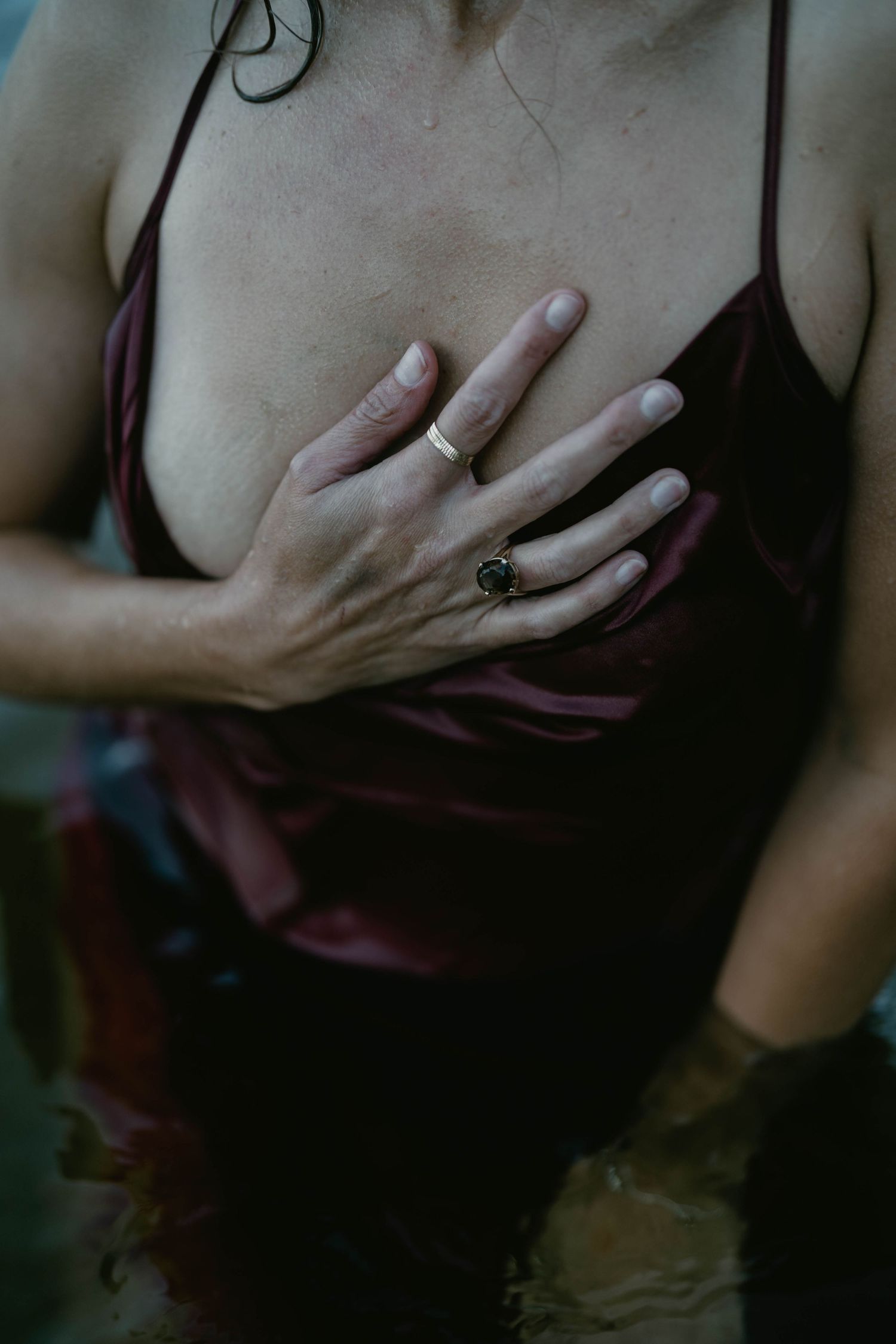 Intimate photoshoot showing details of a burgundy dress and jewelry.
