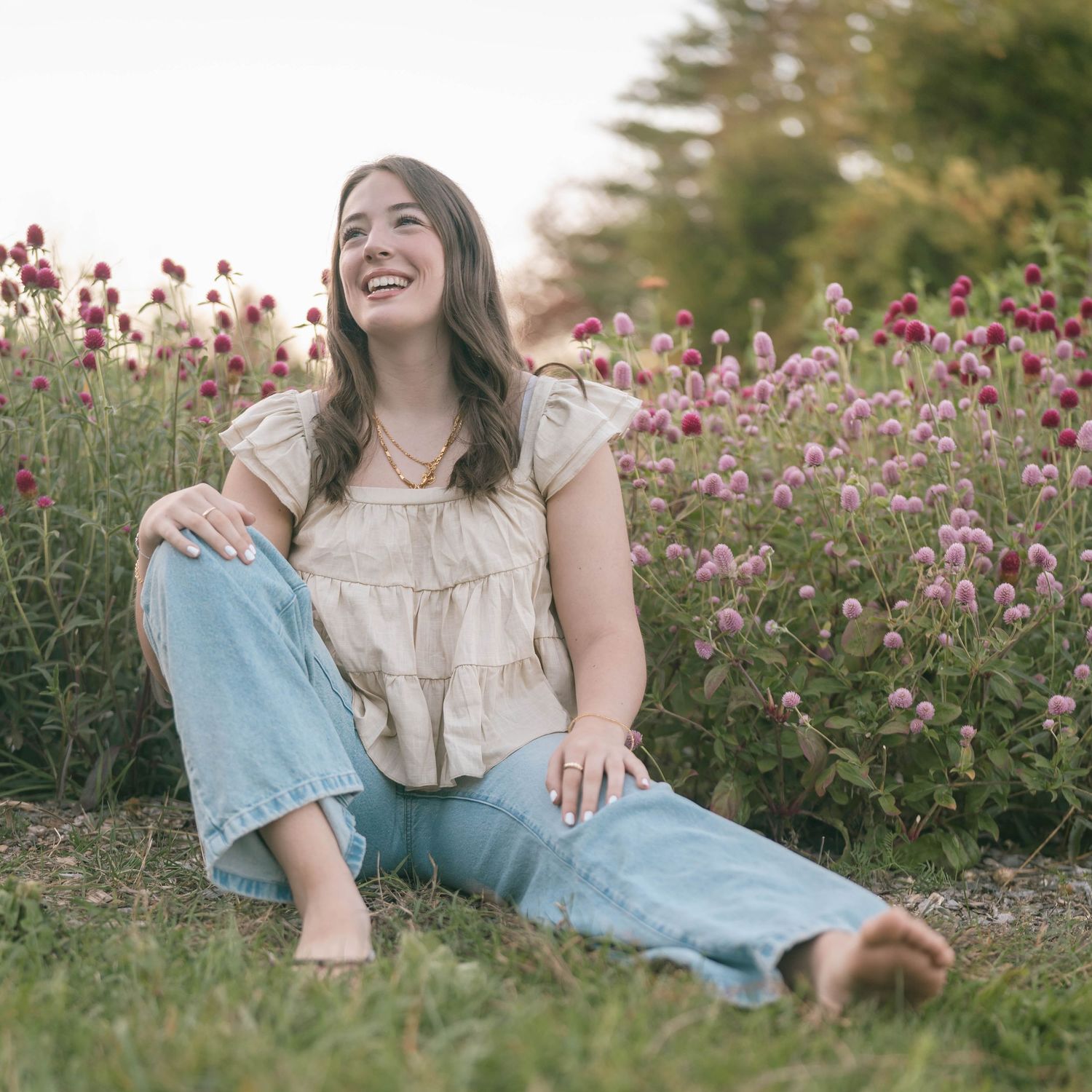 Woman in casual attire relaxing in a blooming flower field during sunset.