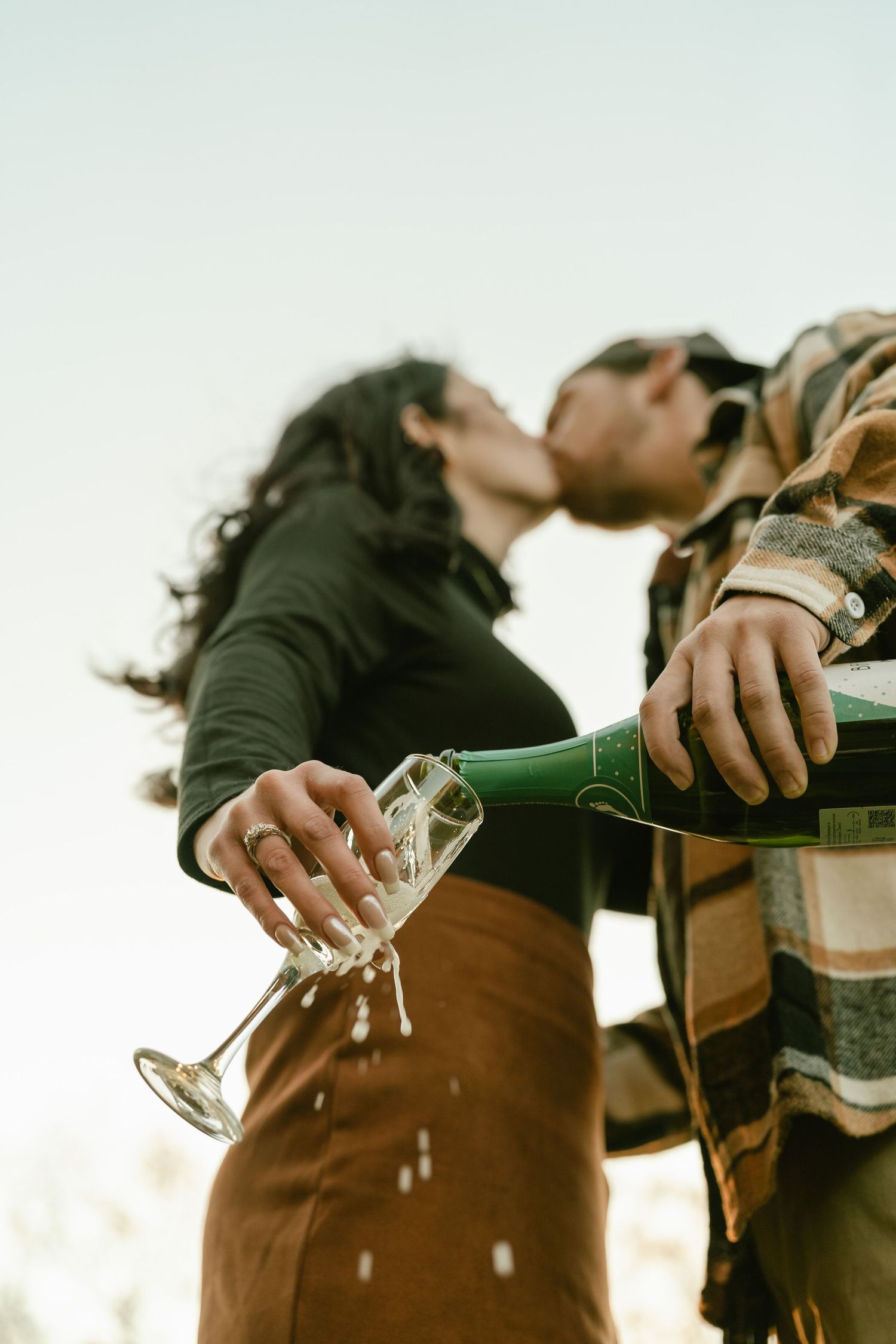 Champagne being poured during a celebration outdoors at sunset.