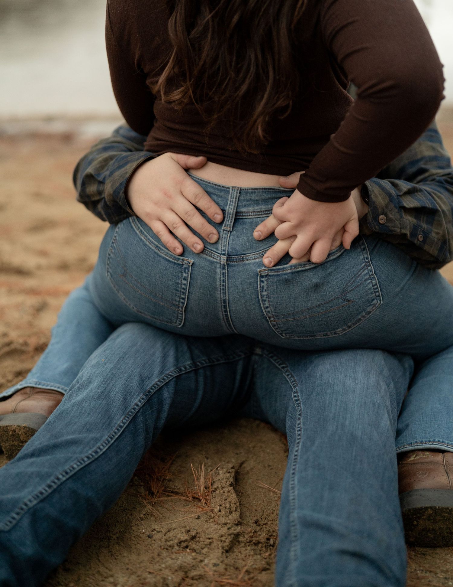 Close-up of couple sitting together on sandy beach.
