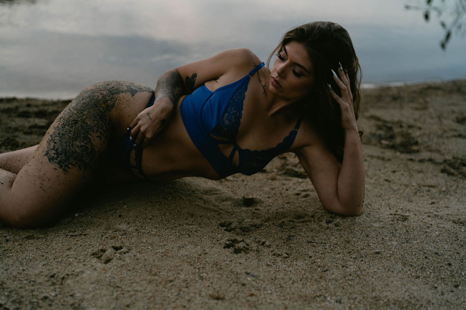Dramatic beach photoshoot with moody lighting and sand textures.