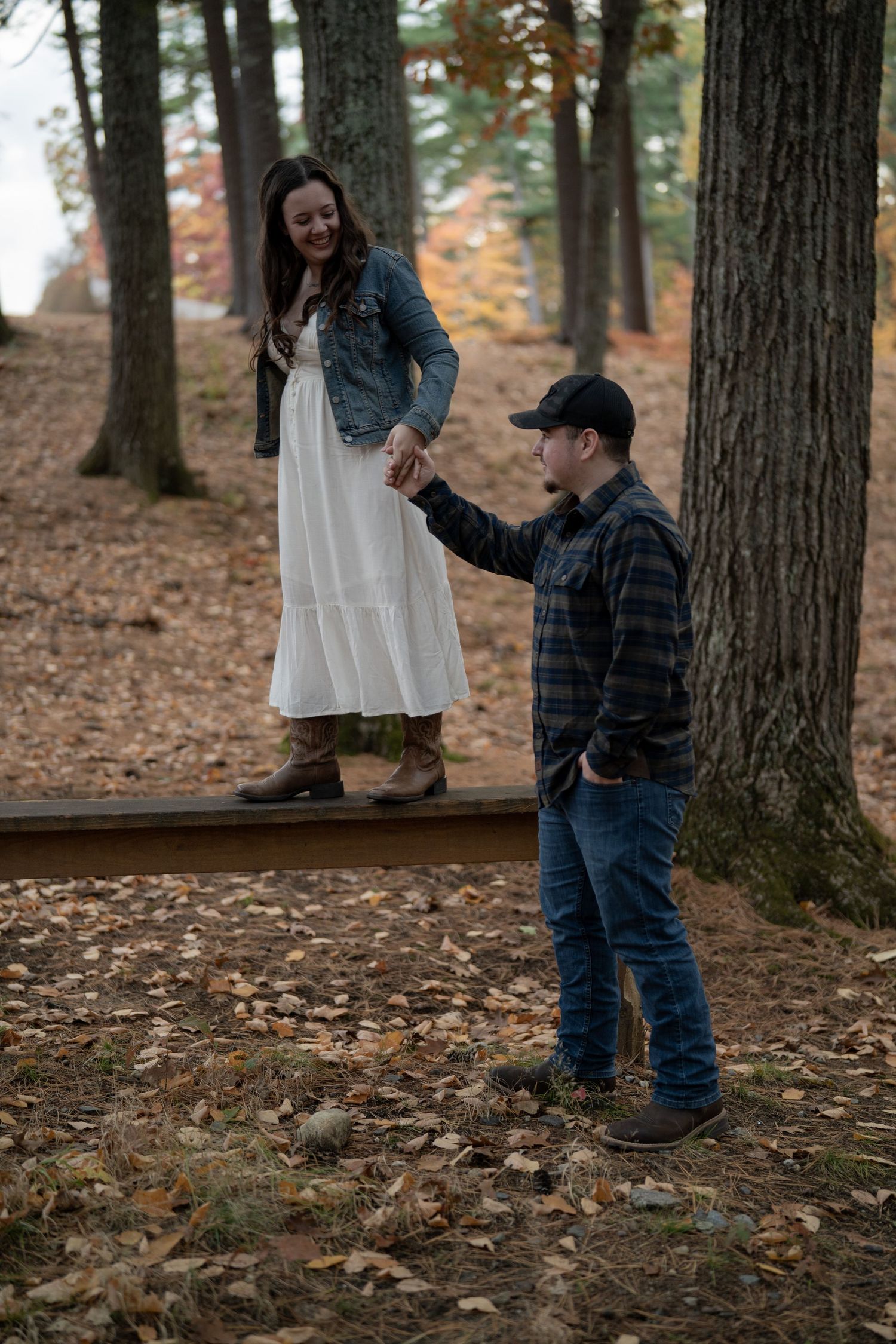 A couple shares a special moment among tall trees in an autumn forest.
