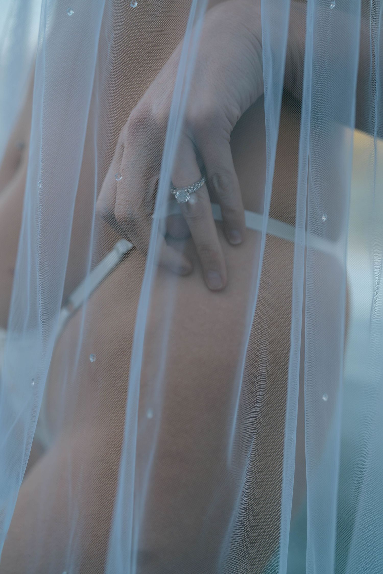 Hands reaching through vertical white bars or slats creating an artistic pattern against a blurred background.