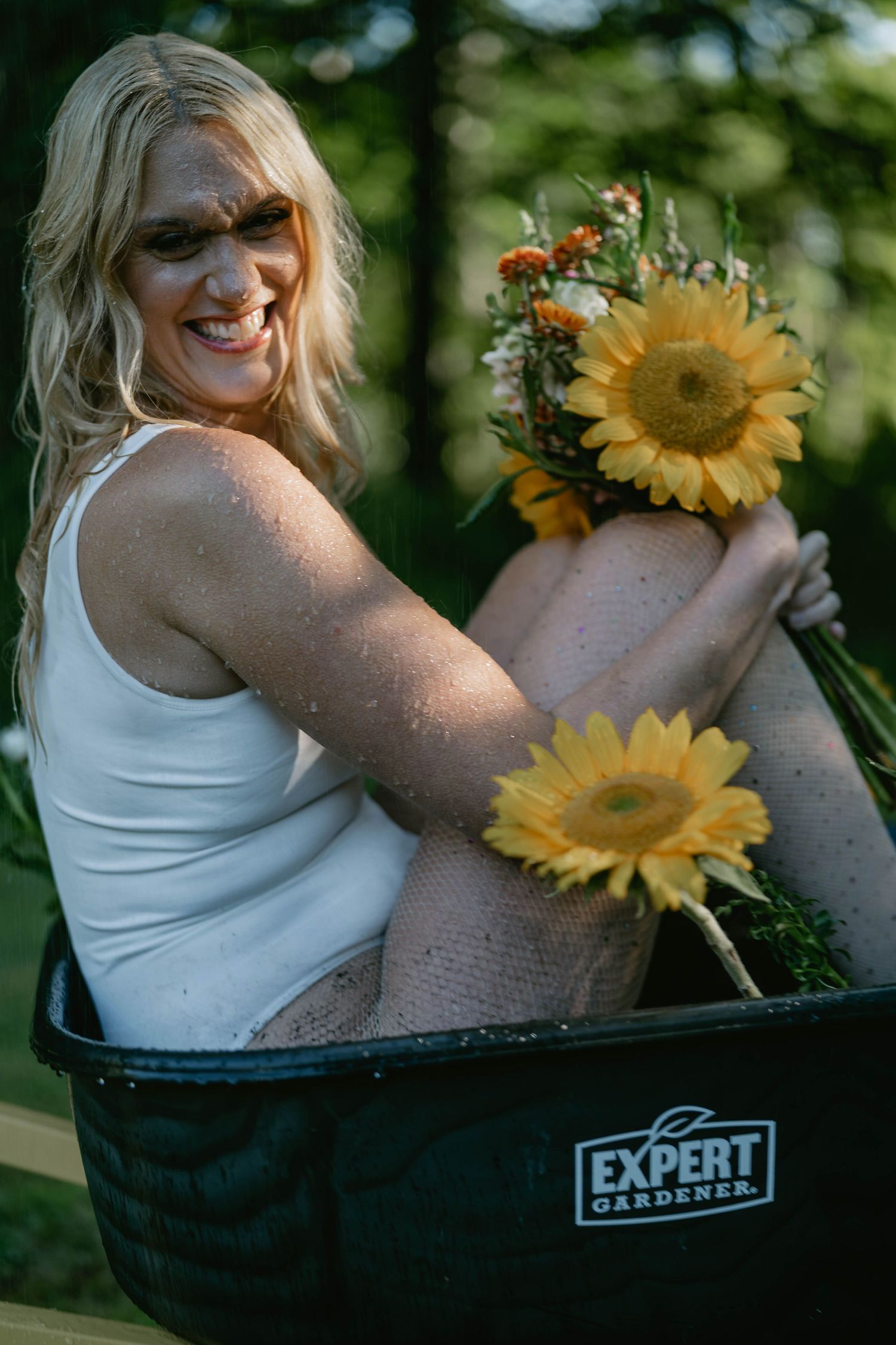 Joyful sunflower photoshoot featuring white tank top and natural outdoor lighting.