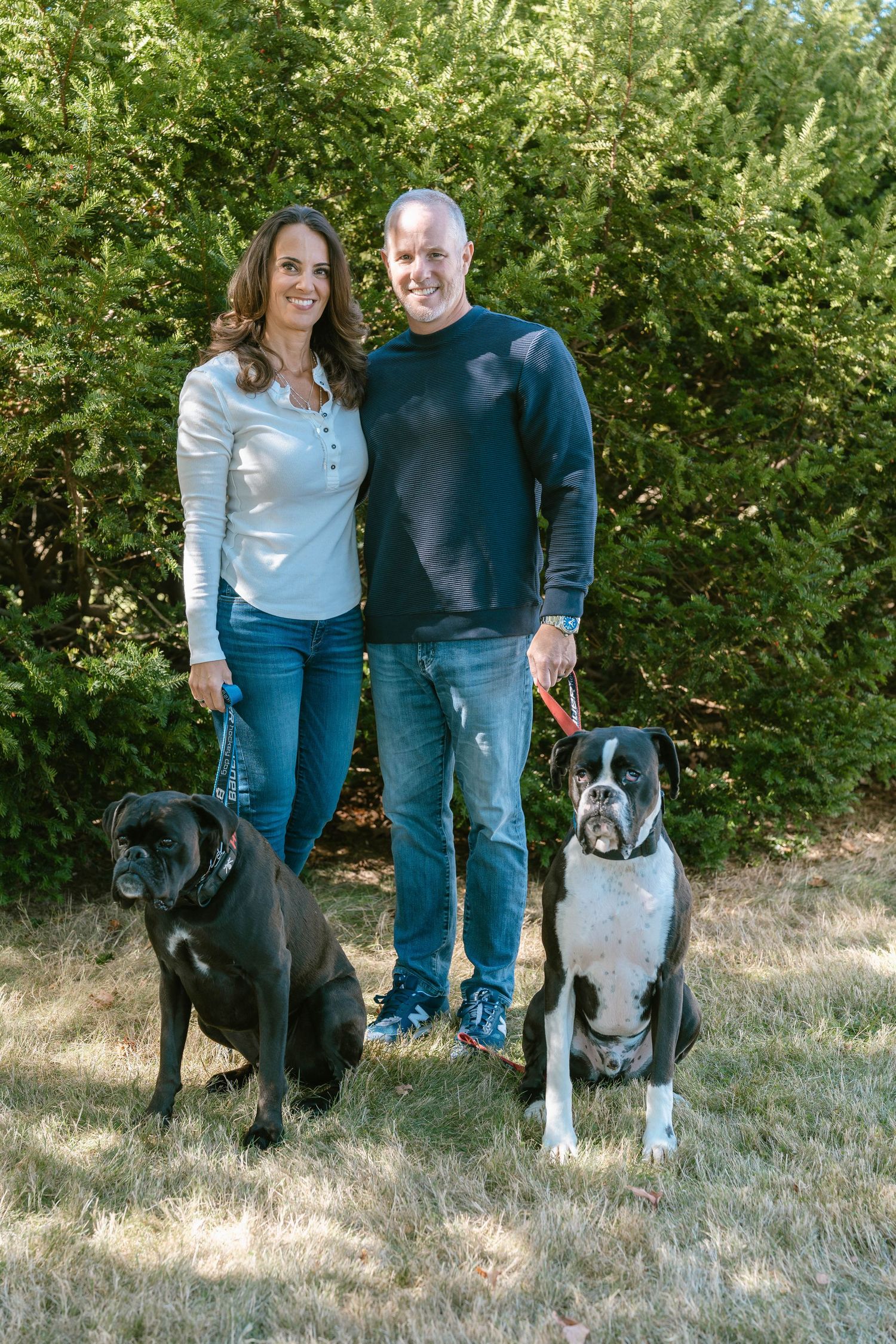 Family standing with their three dogs outdoors during a pet-inclusive photo session.