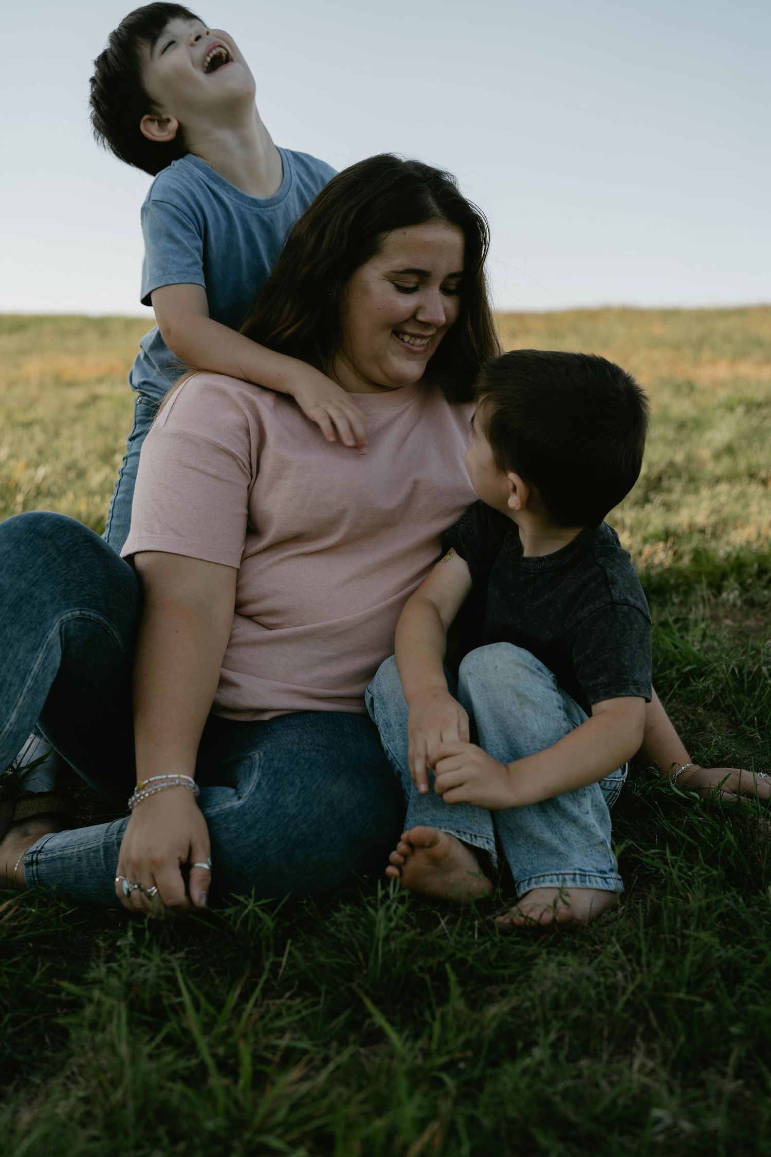 A joyful family moment captured outdoors as they sit together on grass during sunset.