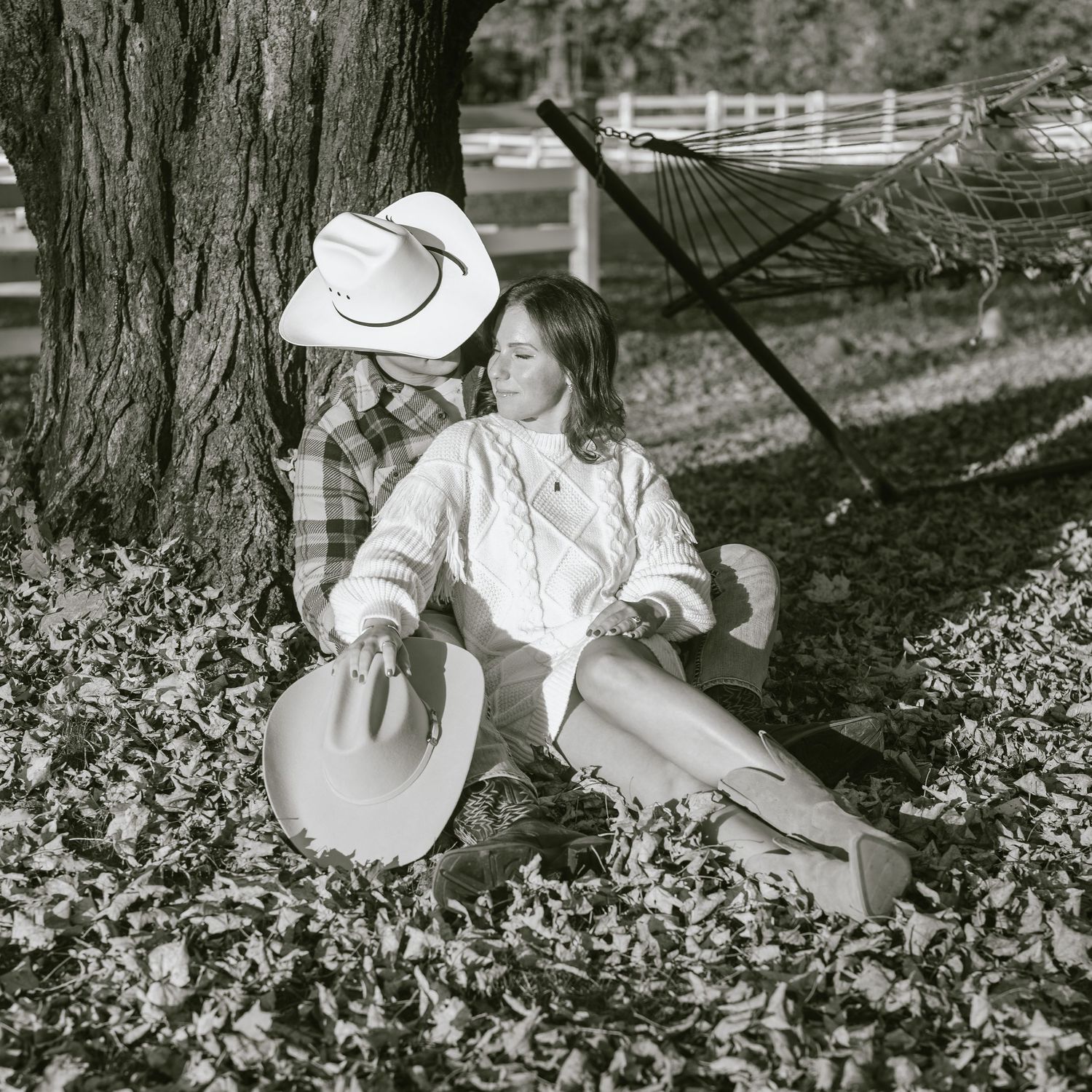 A black and white photo series showing someone sitting in fallen autumn leaves while wearing a white dress.